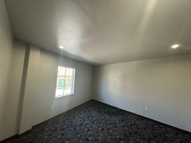Recessed ceiling lighting, a window with exterior architectural details, and patterned carpet flooring