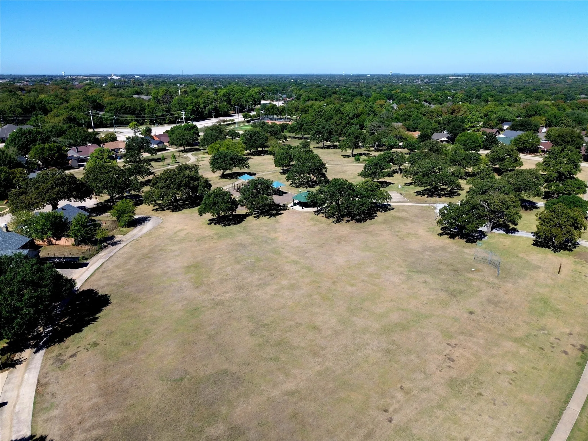 Expansive park setting featuring mature trees, paved pathways, and recreational areas