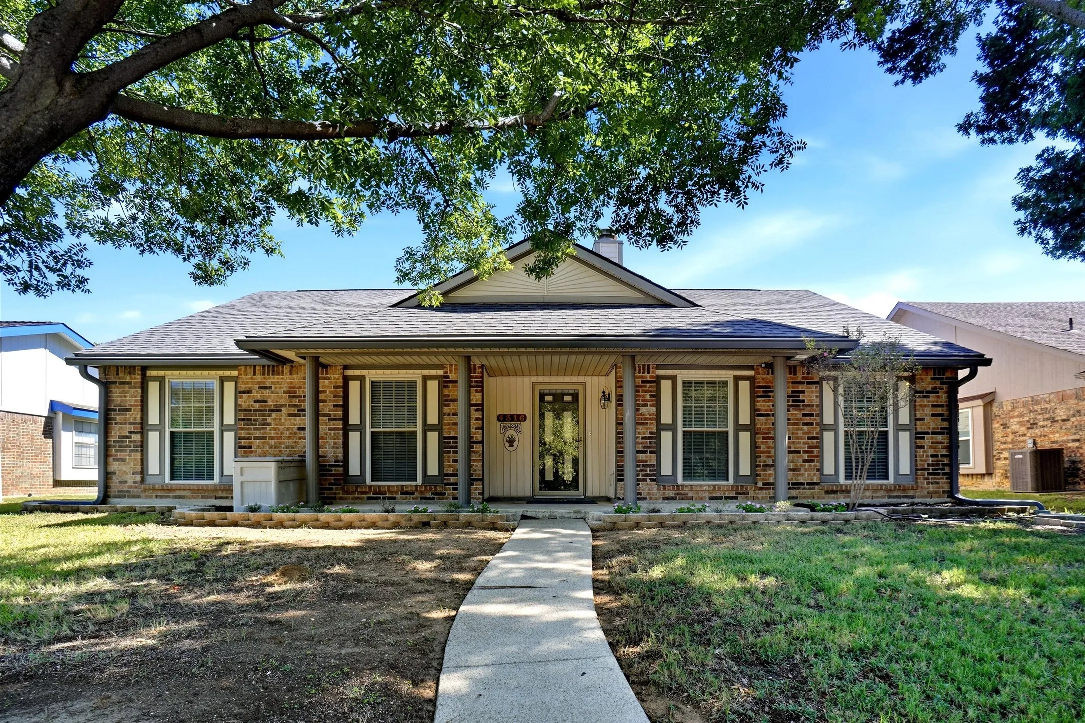 Brick exterior with a covered front porch featuring four support columns, a gabled roofline, and louvered shutters