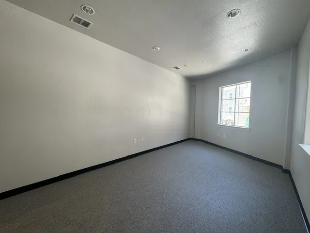 Recessed lighting, light gray wall finish, dark gray carpet, white window trim, and black baseboards