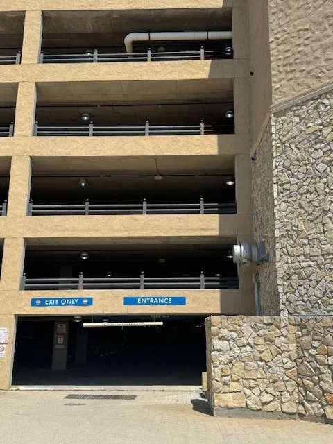 Multi-level parking structure with textured concrete exterior and stone facade detailing