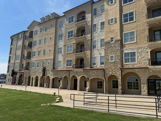 Multi-story stucco and stone exterior with multiple balconies, arched ground-level entryways, and varied window styles