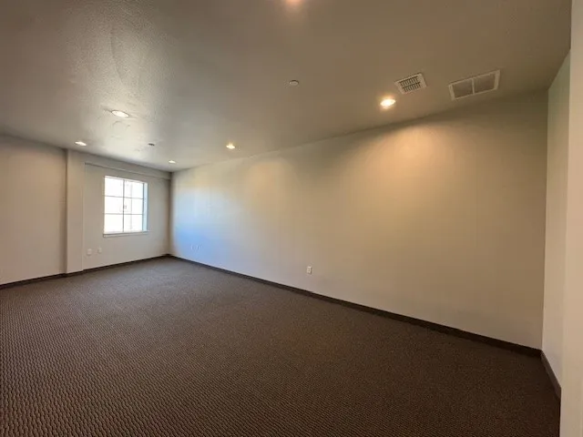 Expansive room featuring recessed lighting, a window with grid detailing, and patterned carpet flooring
