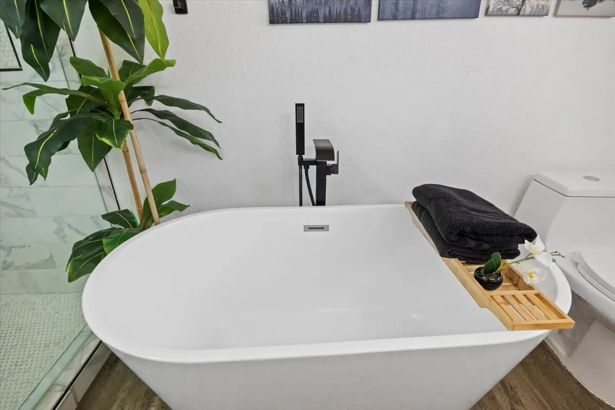 White freestanding tub with a matte black floor-mounted faucet.