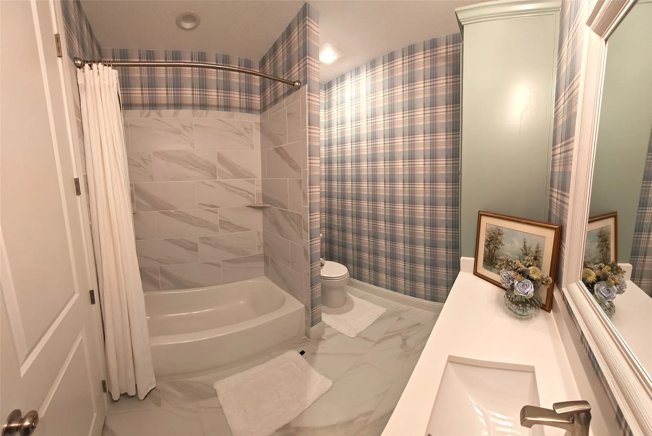 Bathtub with tiled surround, single vanity with integrated sink, wall-mounted mirror, and tiled flooring