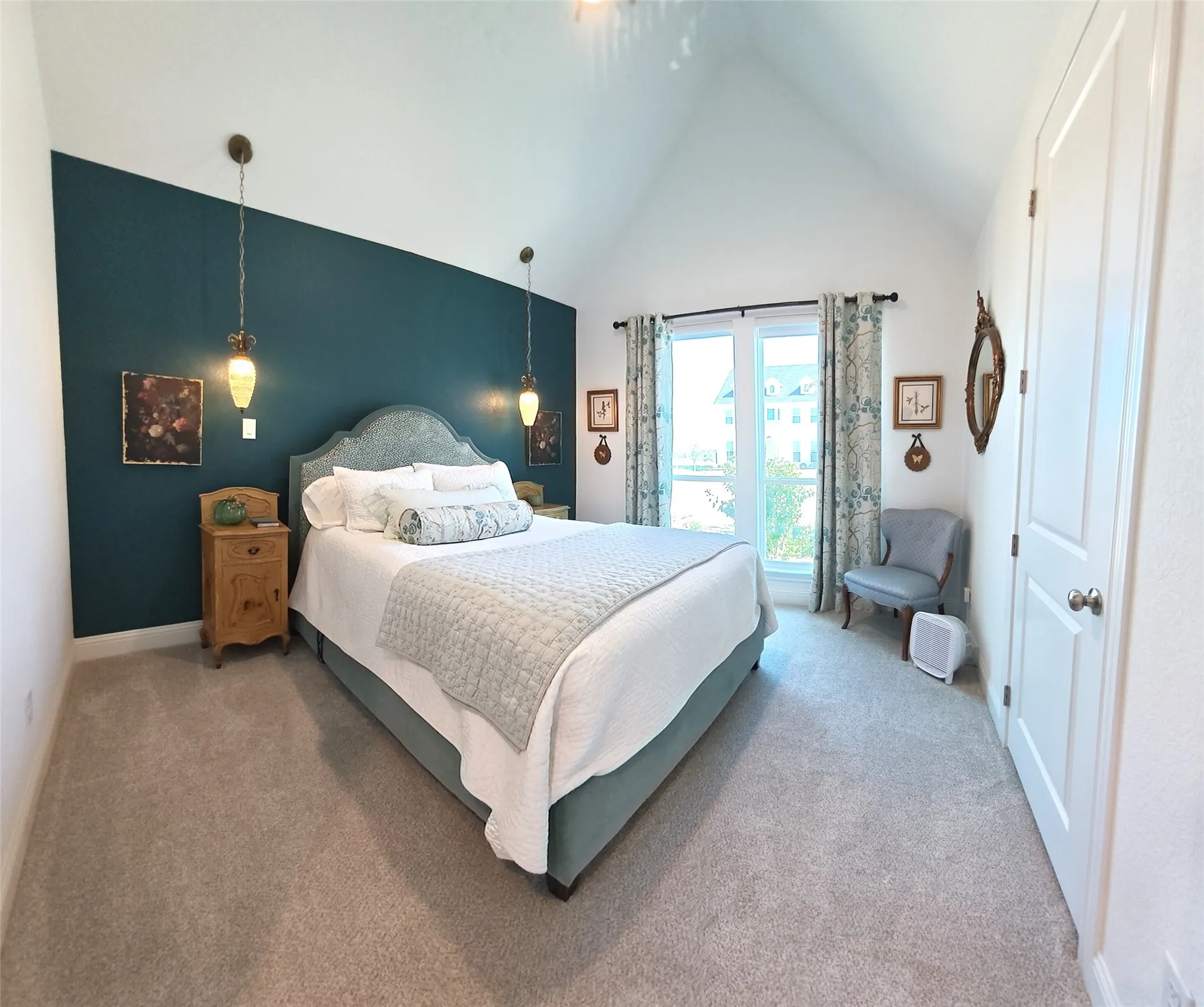 Vaulted ceiling with overhead lighting, featuring a contrasting accent wall with two pendant lights, a double window with a transom, and light-toned carpet flooring
