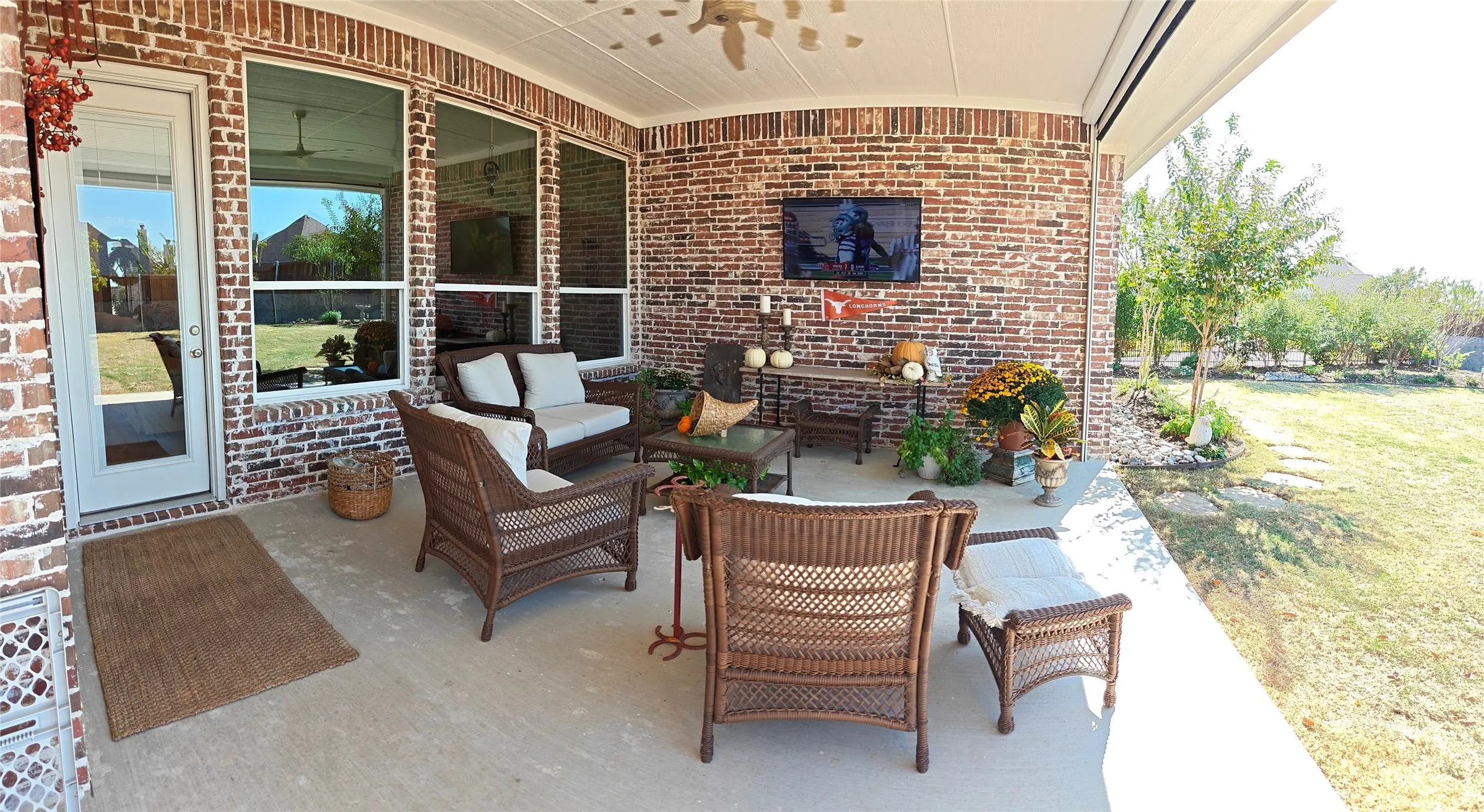 Covered patio featuring a concrete surface, brick exterior wall, multiple large windows, and a ceiling fan