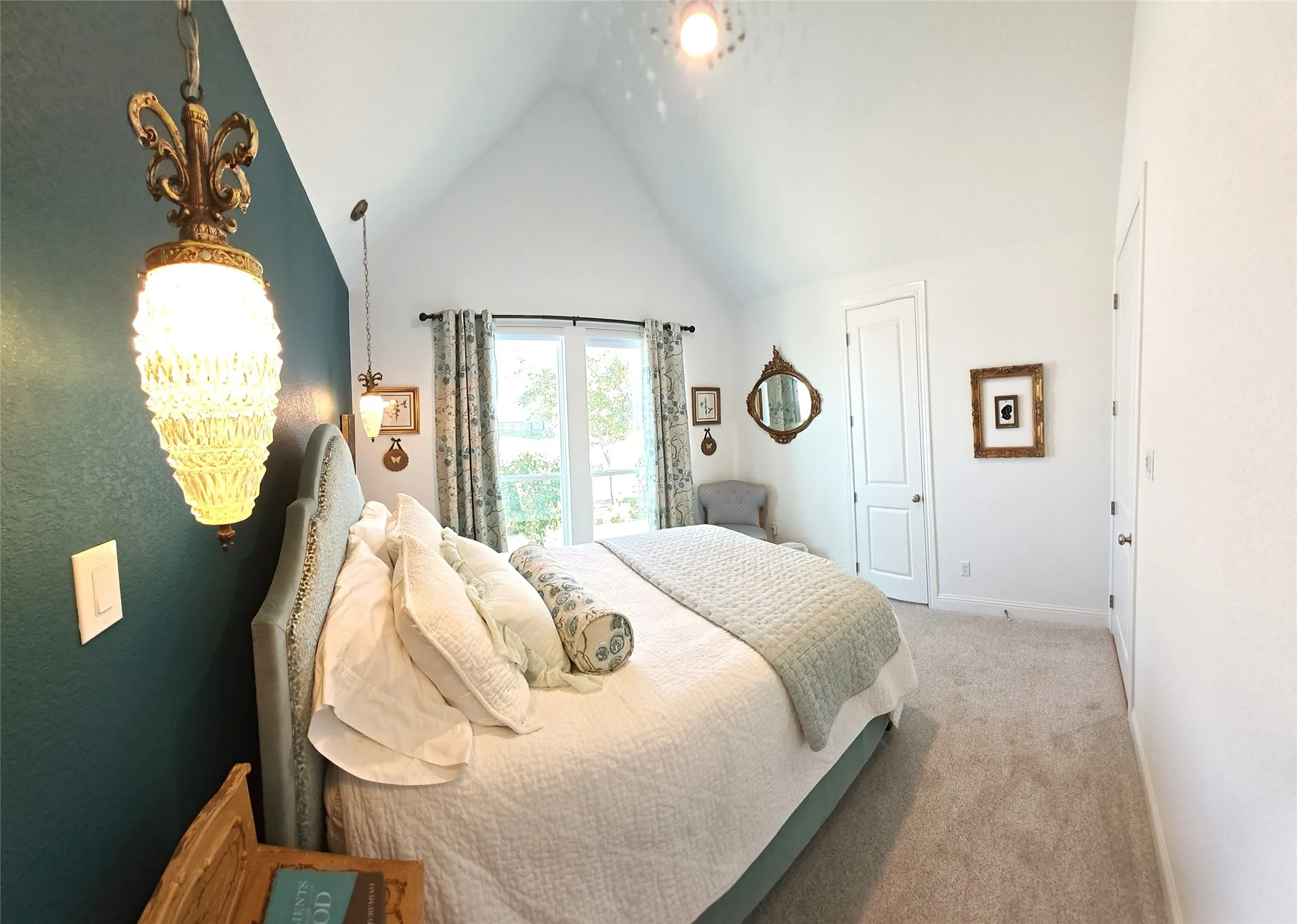 Vaulted ceiling, two-panel interior doors, light-colored carpeting, pendant lighting, and an exterior glass door