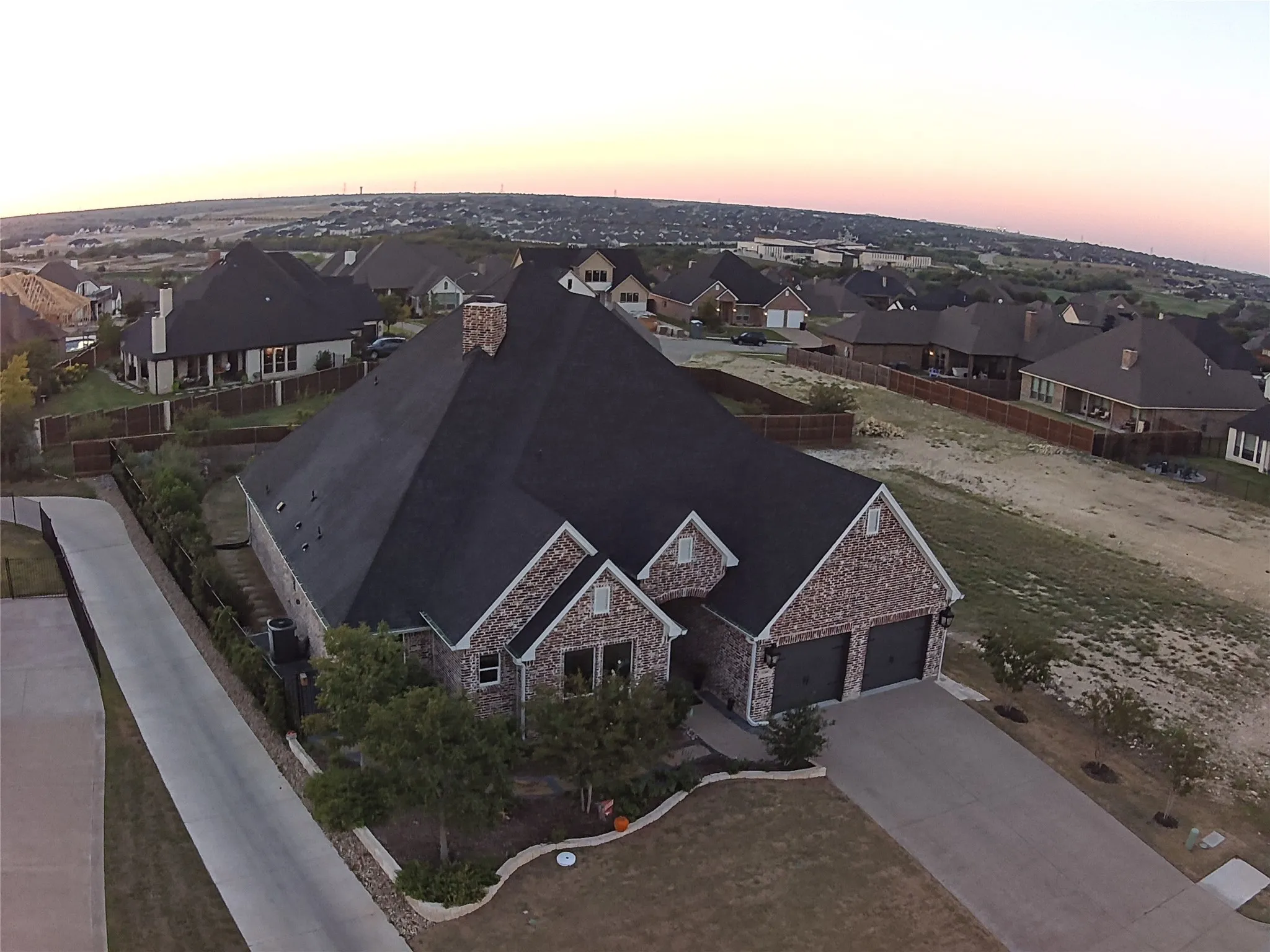 Brick and stone exterior with a dark shingle roof, featuring a two-car garage, concrete driveway, and landscaped front yard