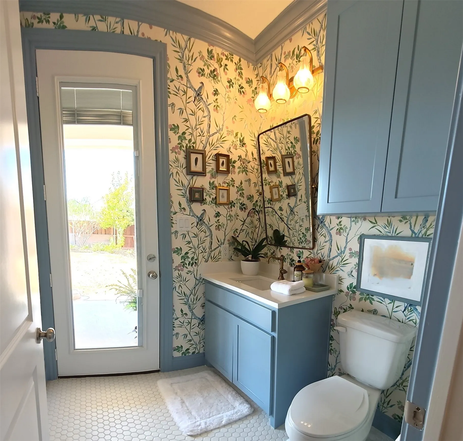 Powder room featuring a single vanity with a white countertop, blue cabinetry, decorative wallpaper, and hexagonal tile flooring