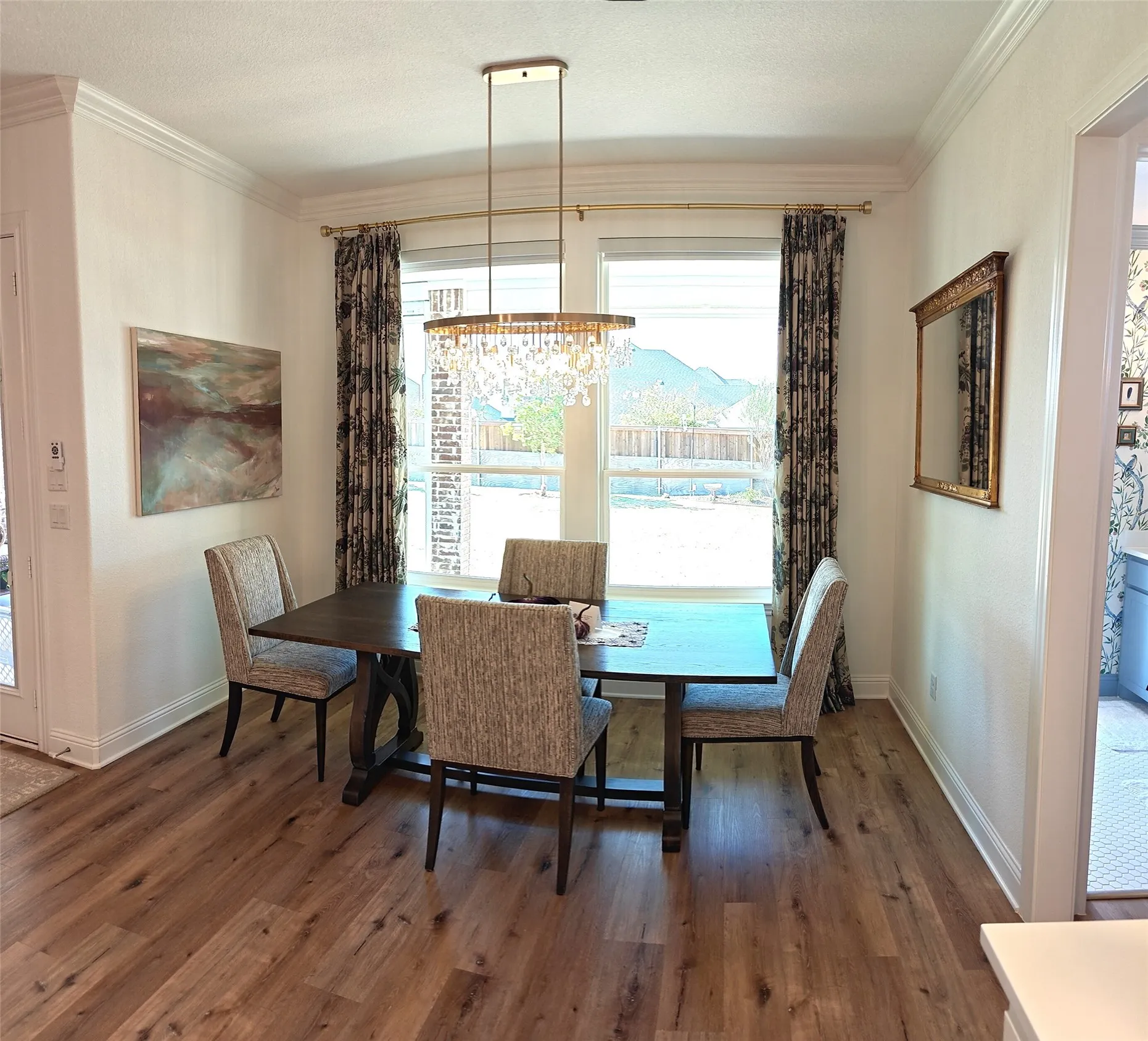 Wood-finish flooring, crown molding, and a crystal chandelier