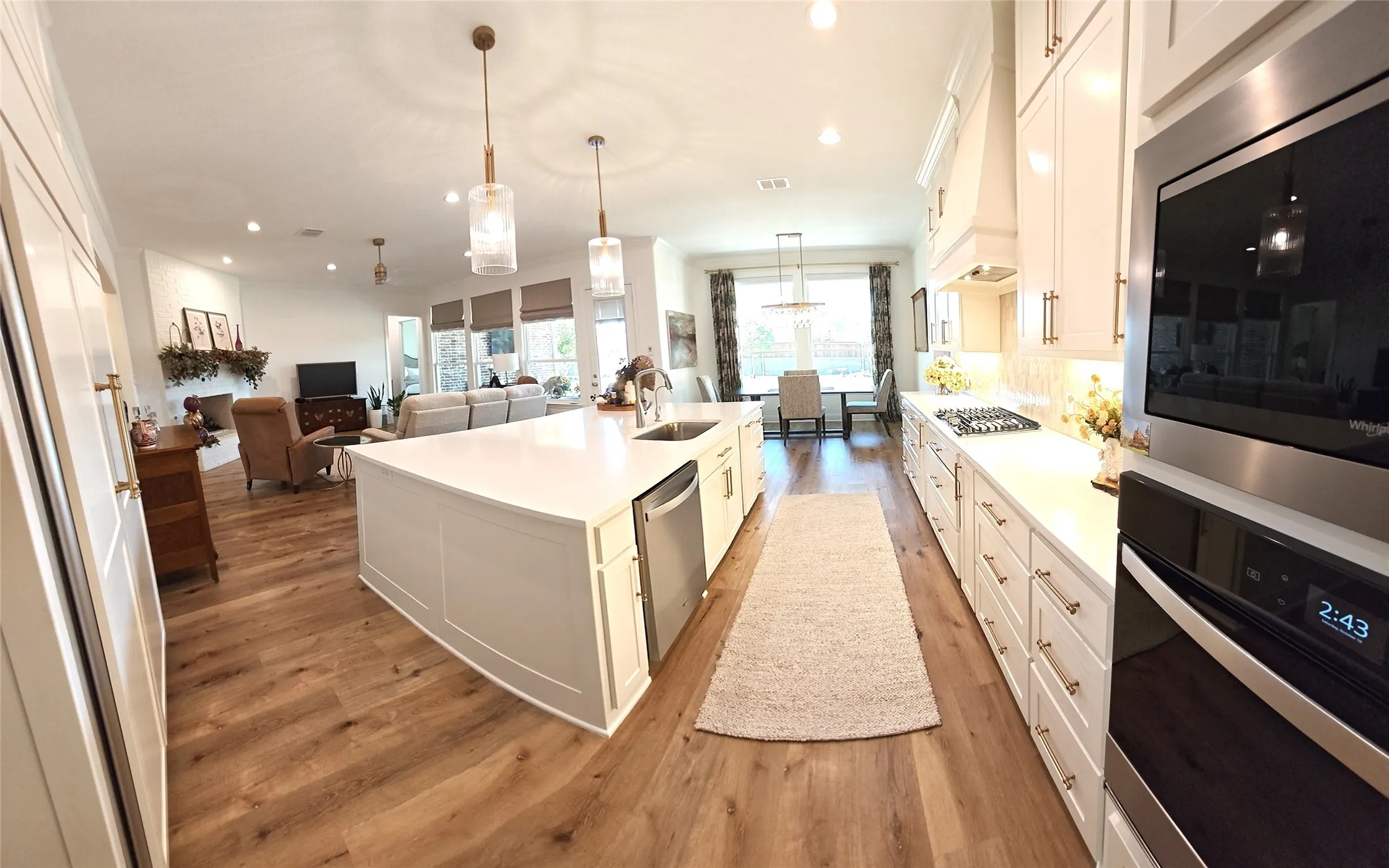 Gourmet kitchen with an expansive island, stainless steel appliances, white cabinetry, and wood-finish flooring
