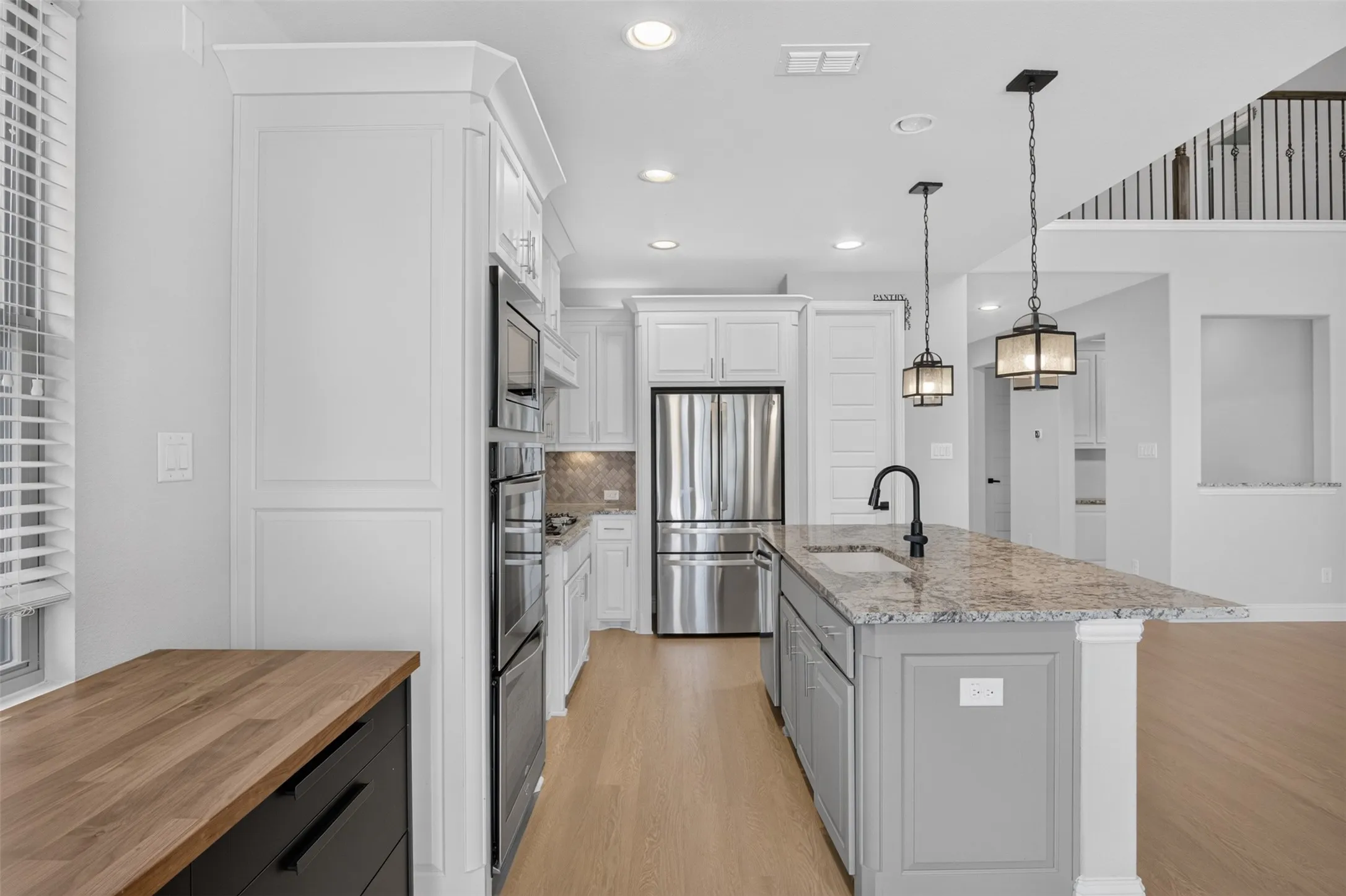 Modern kitchen featuring white cabinetry, stainless steel appliances, a center island with a speckled countertop, and recessed lighting