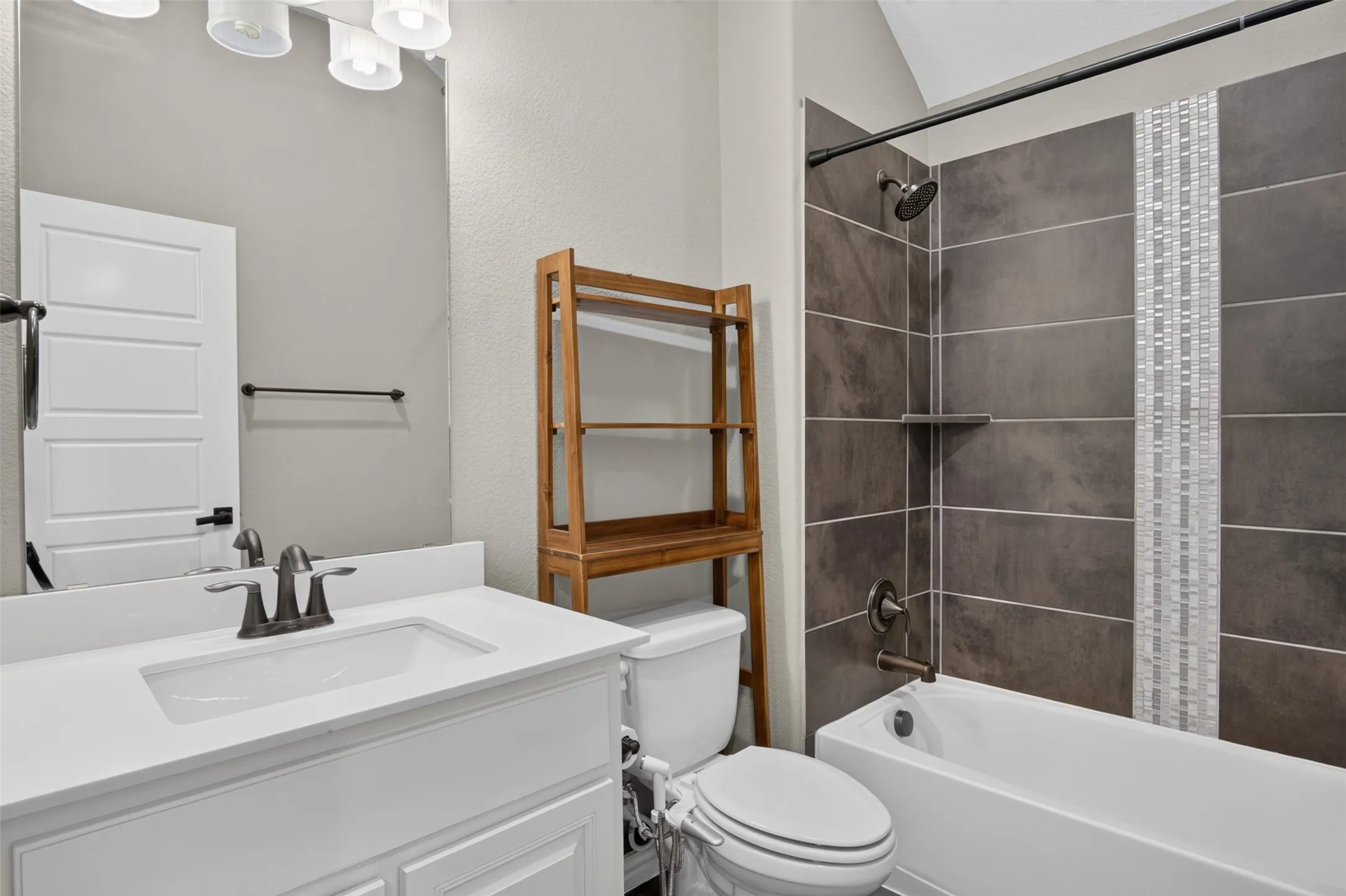 White vanity with a rectangular sink, bronze-finish faucet, and overhead lighting
