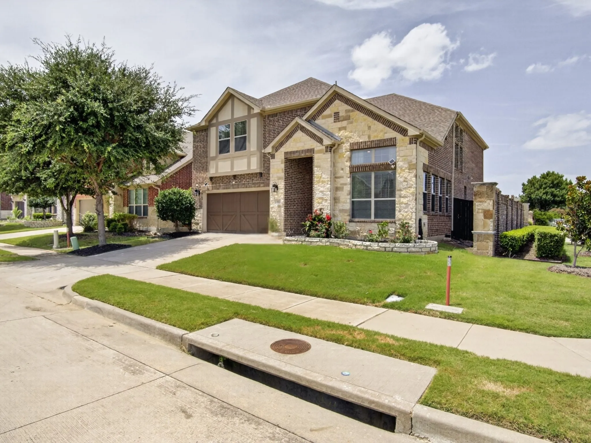 Two-story residence featuring a brick and stone facade, gabled rooflines, and an integrated two-car garage with patterned doors