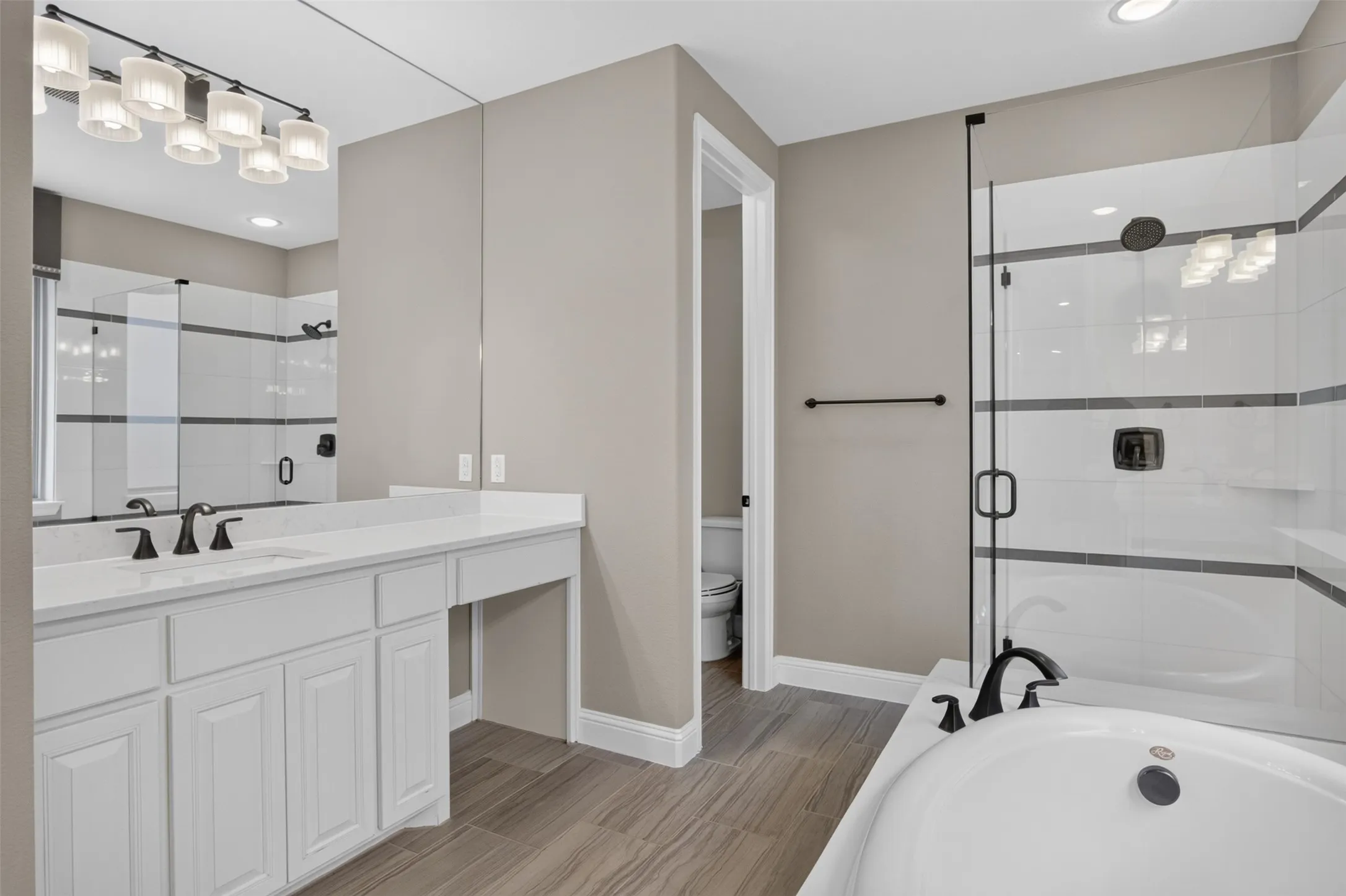 Expansive vanity with a white countertop and dual sinks, complemented by a large wall-mounted mirror and contemporary light fixture