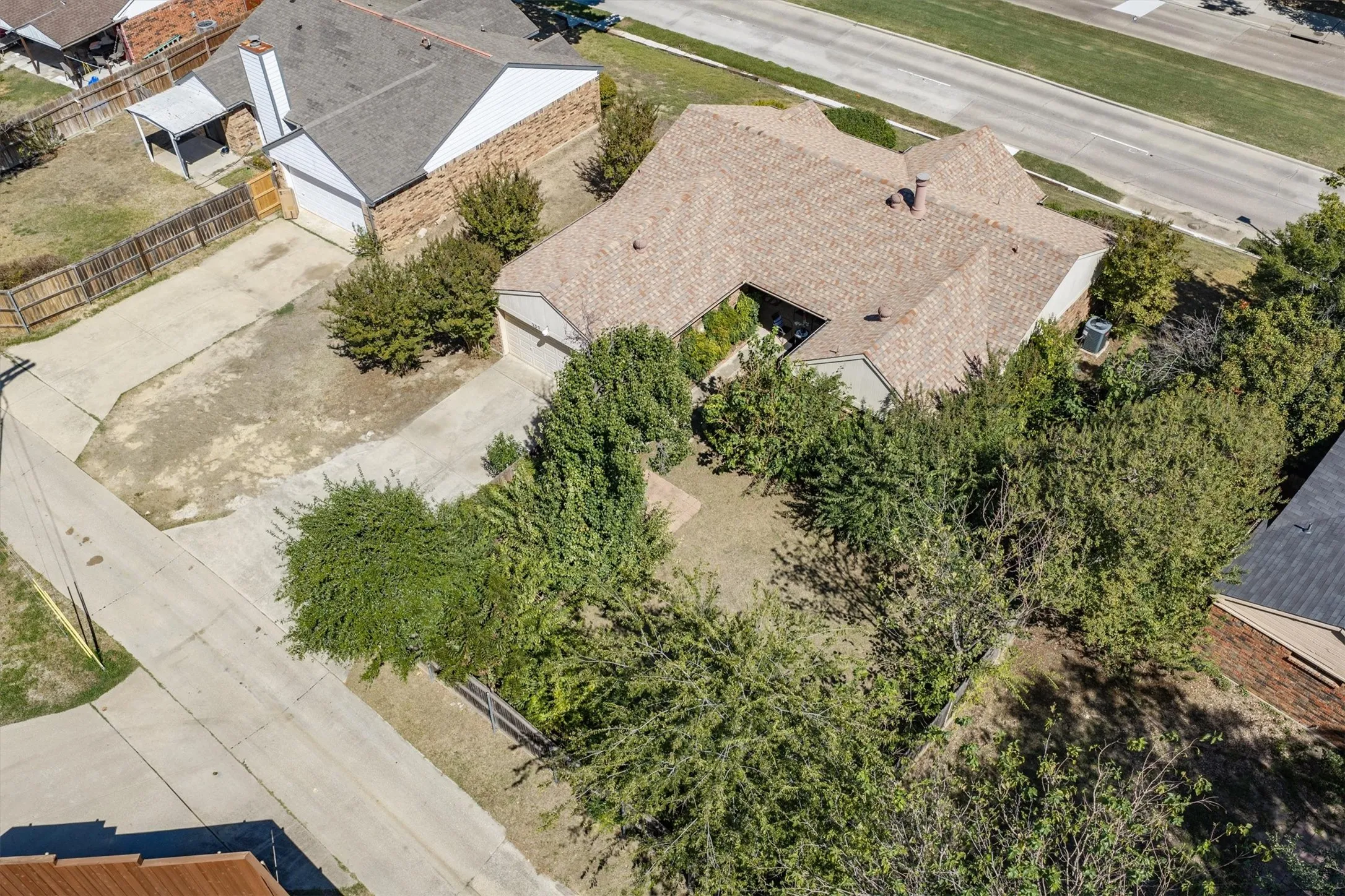 Expansive property featuring a concrete driveway, mature trees, and a shingle roof