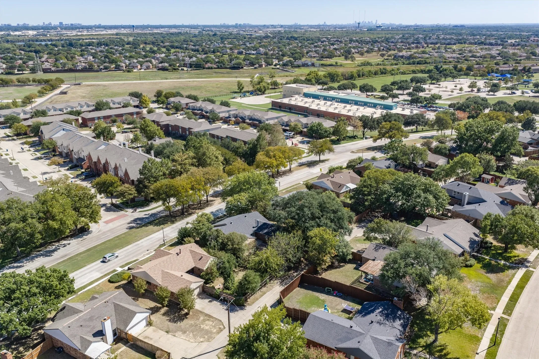 Residential neighborhood featuring single-story homes, mature trees, and paved roads
