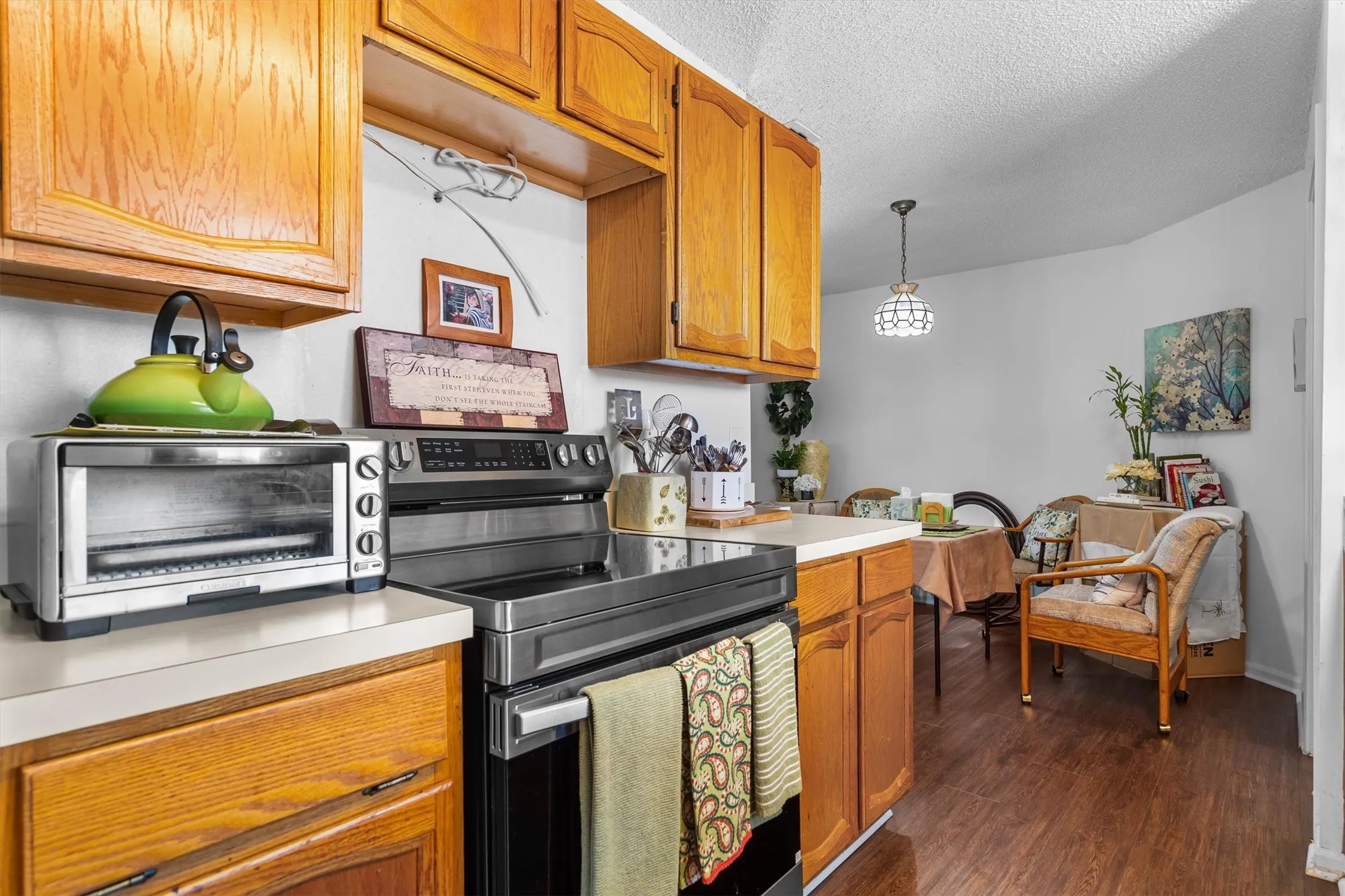 Wood-finish flooring, wood cabinetry, light-colored countertops, and a built-in range