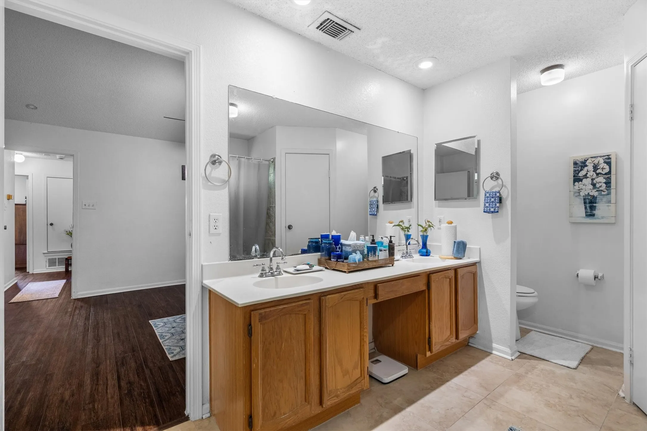 Double vanity with integrated sinks, wood cabinetry, expansive mirror, and overhead recessed lighting