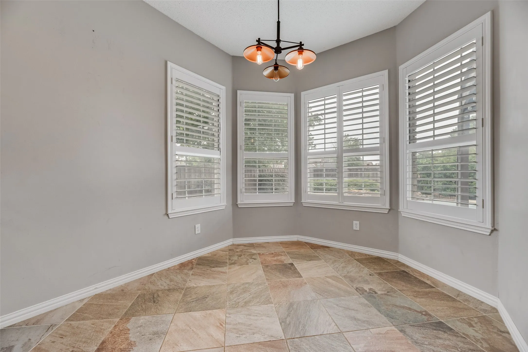 Bay window with plantation shutters and a contemporary pendant light fixture
