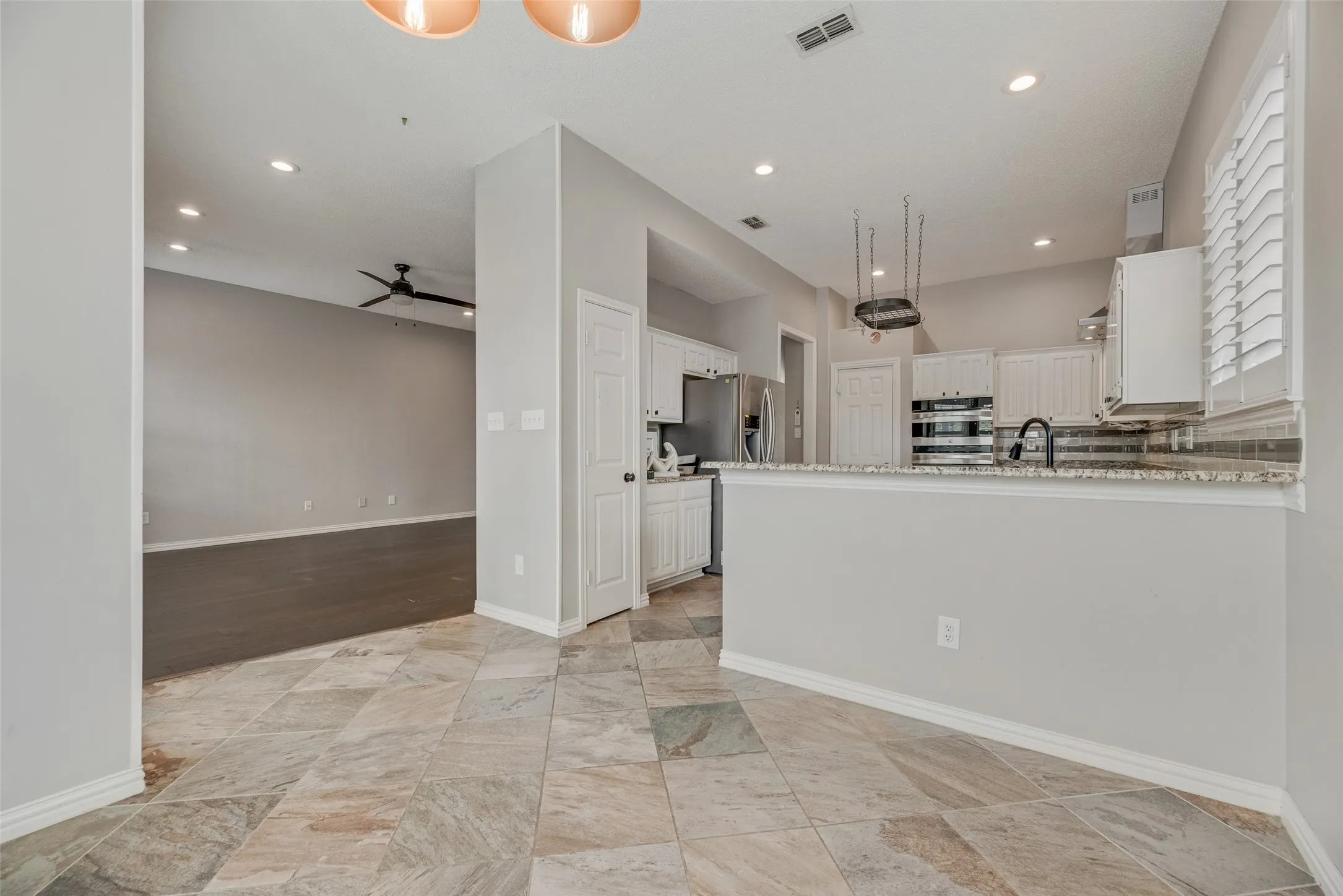 Kitchen featuring a breakfast bar with granite-style countertop, white cabinetry, integrated stainless steel appliances, and tile flooring