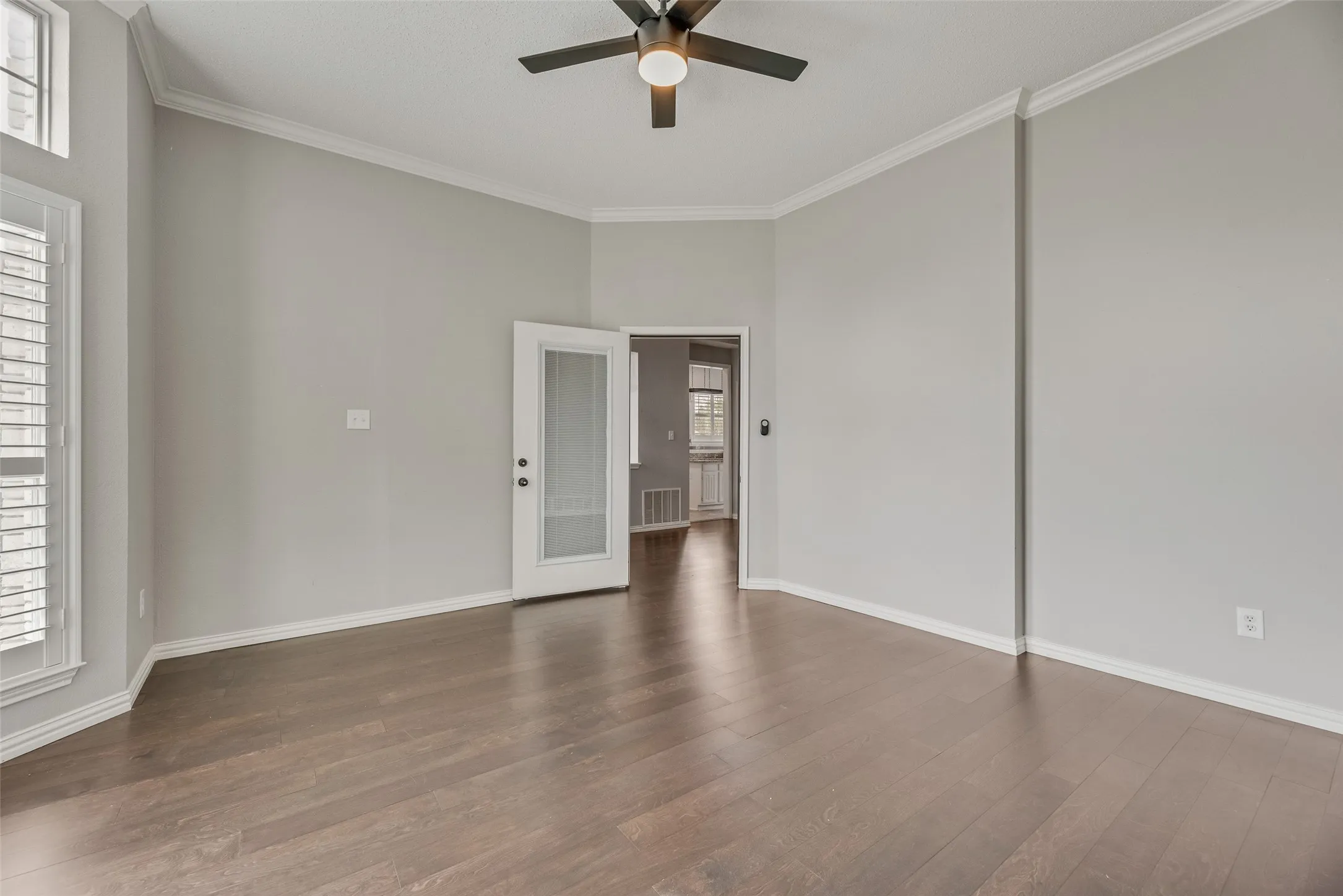Hardwood flooring, crown molding, white plantation shutters, and a ceiling fan with integrated lighting