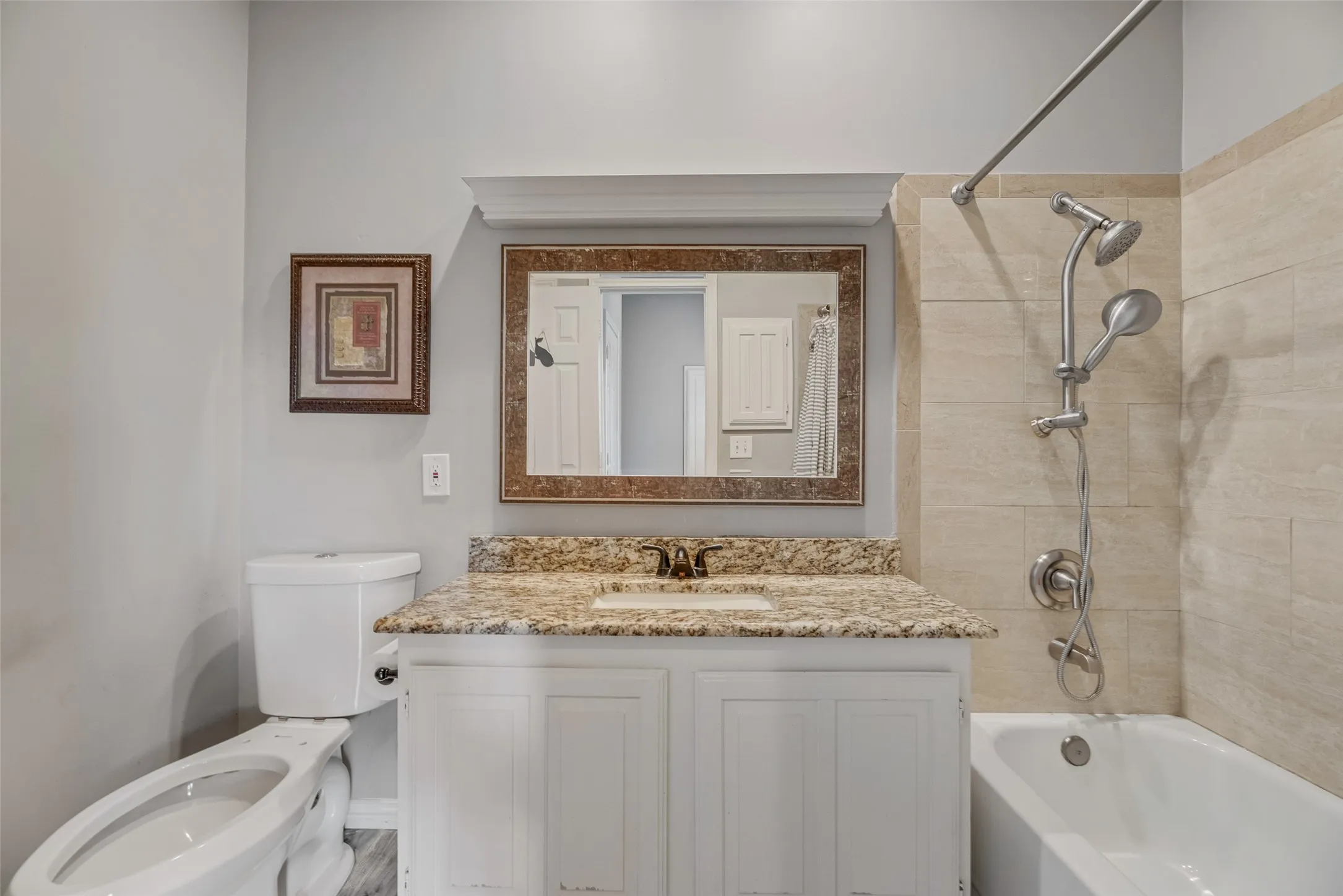 White vanity with a granite-style countertop, undermount sink, and polished chrome faucet