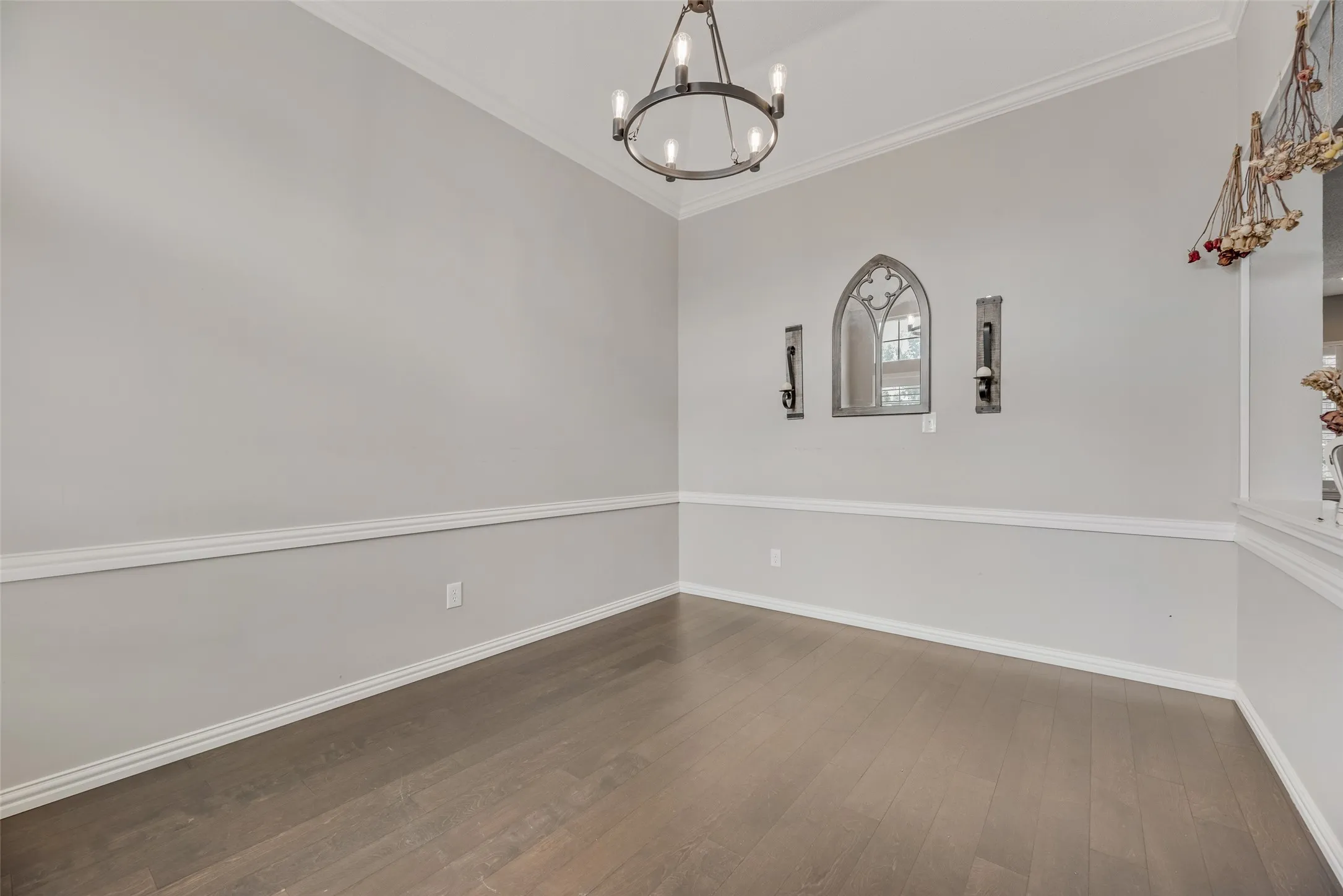 Wood-finish flooring, chair rail molding, crown molding, and an overhead chandelier