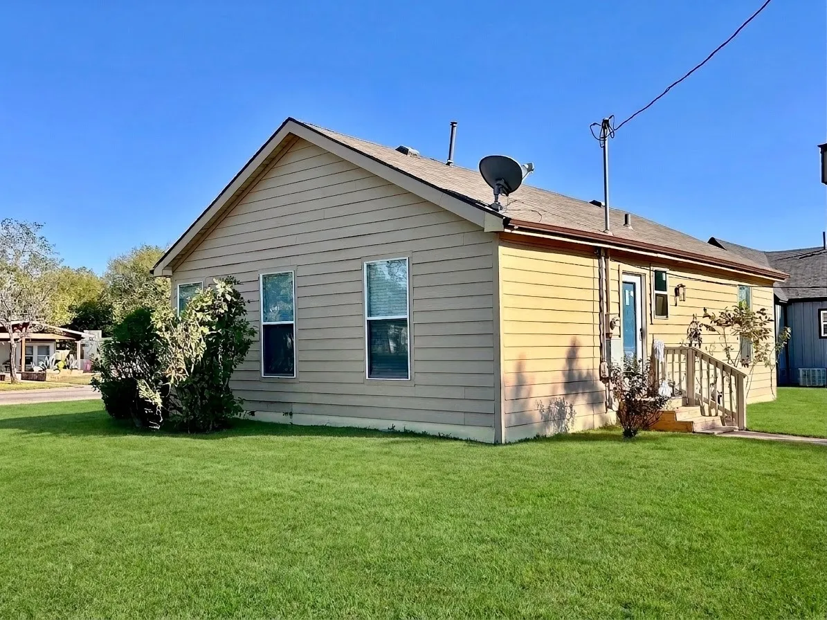 Exterior siding with multiple windows, a gabled roof, and a side entrance with stairs