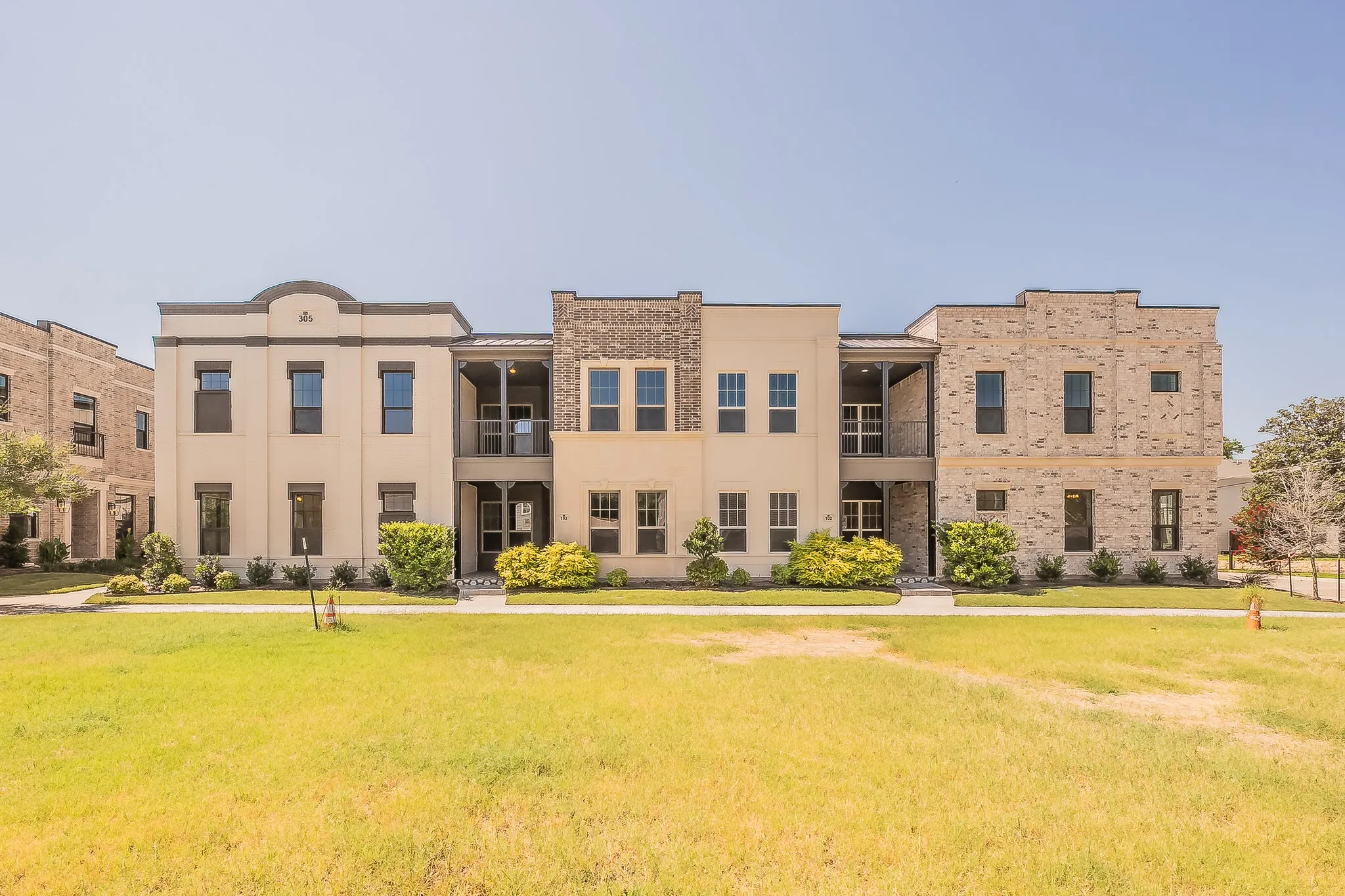 Contemporary multi-story facade featuring light-colored stucco and brick accents
