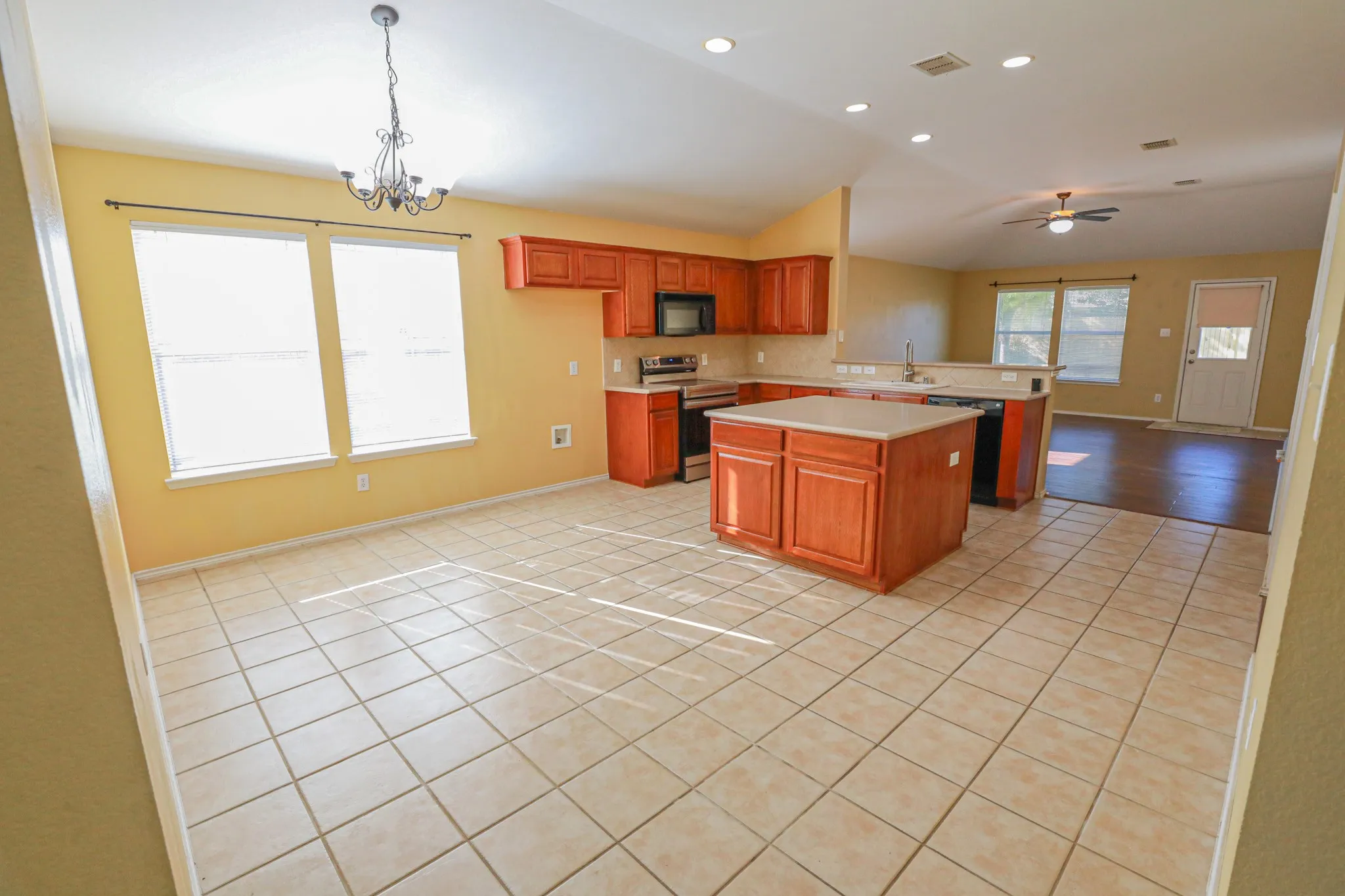 Ceramic tile flooring, kitchen island, wood-finish cabinetry, stainless steel appliances, and vaulted ceiling