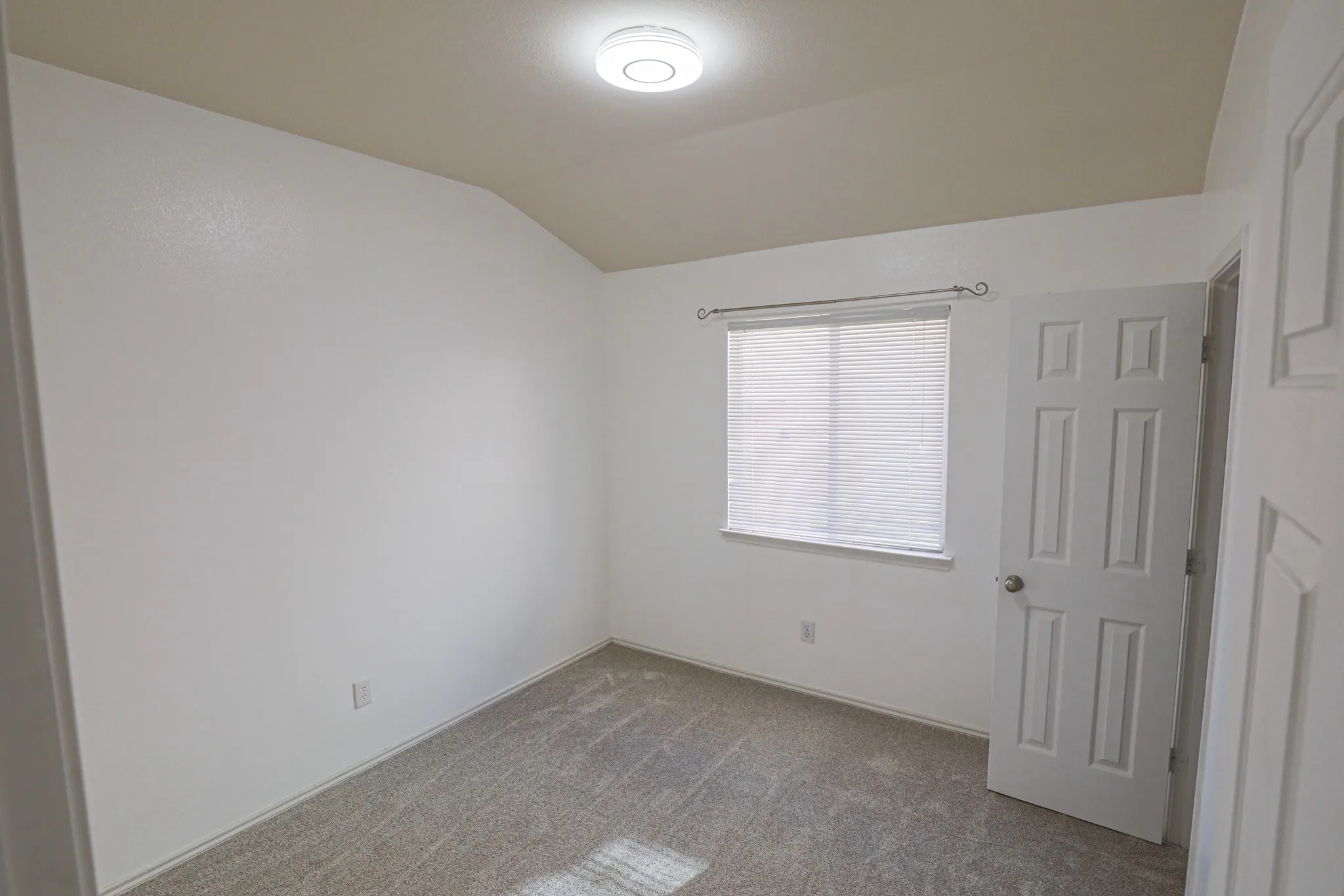 Neutral tone paint, textured walls, window with horizontal blinds, flush mount ceiling light, and carpeted flooring