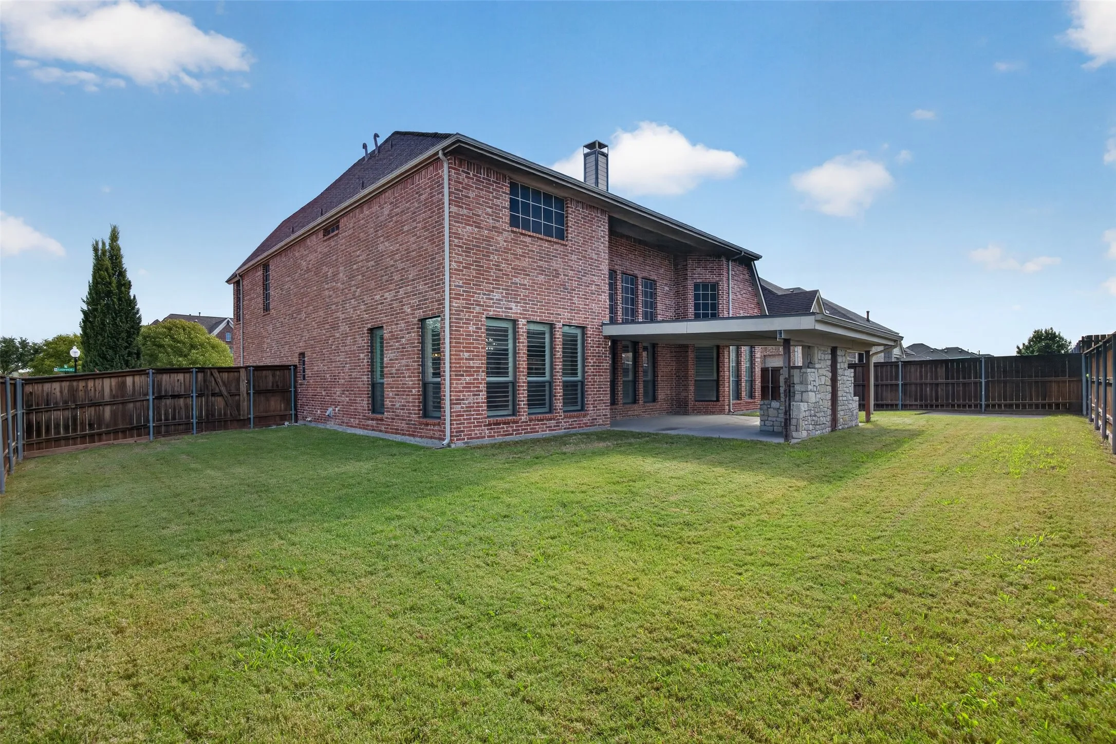 Large backyard with covered patio and stone kitchen area built-in