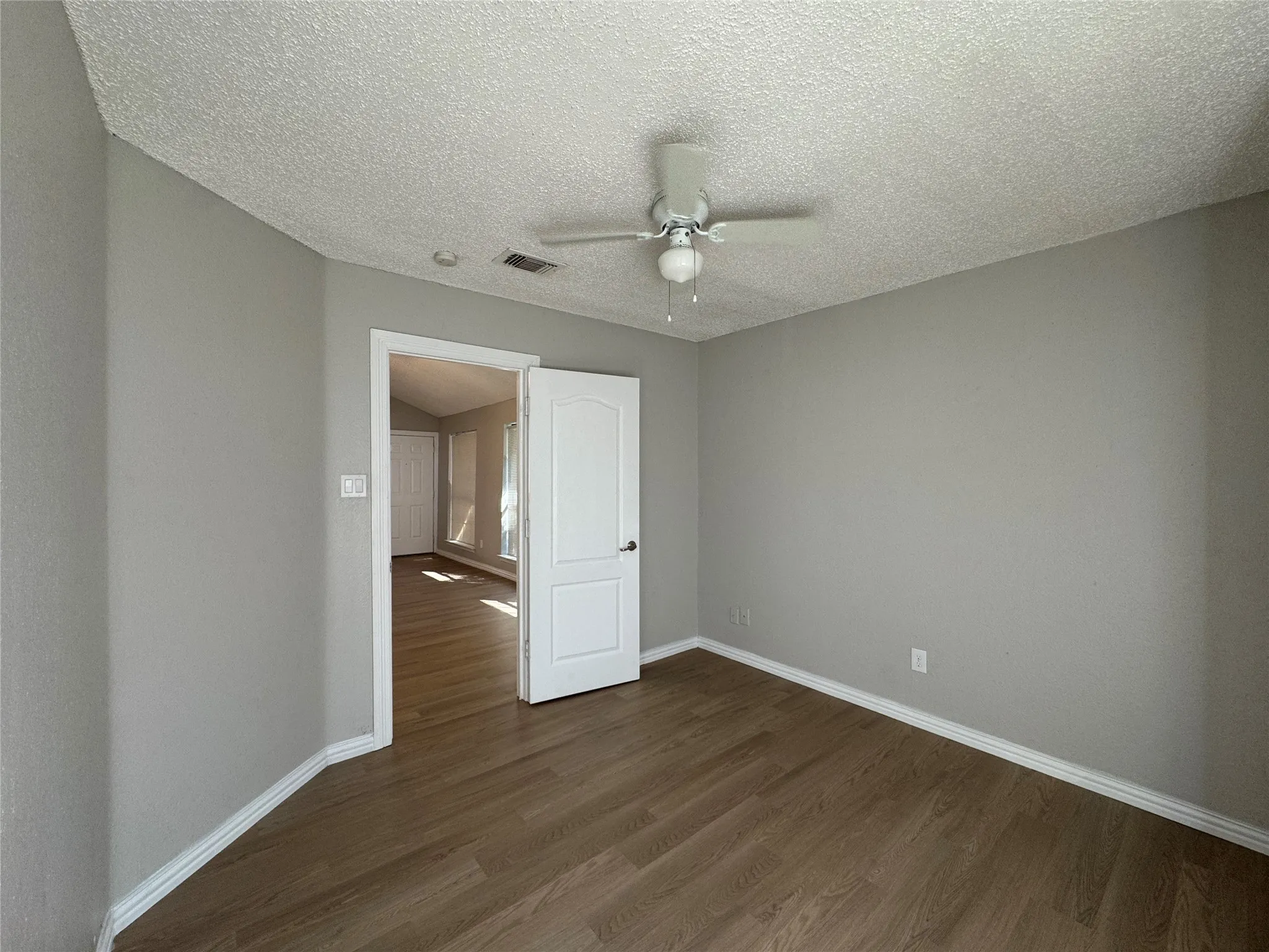 Wood-finish flooring with light gray walls, white trim, and a ceiling fan