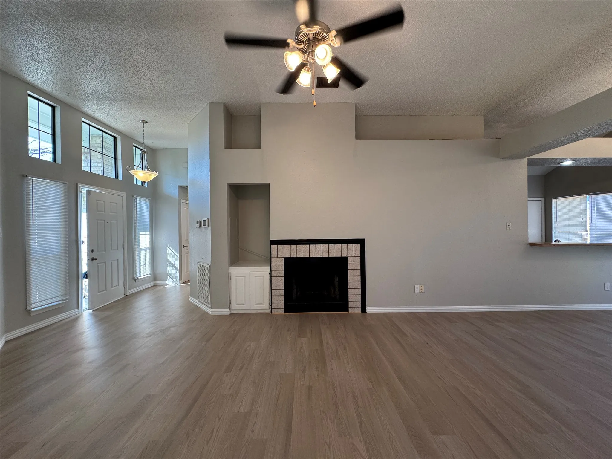 Spacious living area featuring wood-finish flooring, a fireplace with a brick surround, and built-in cabinetry