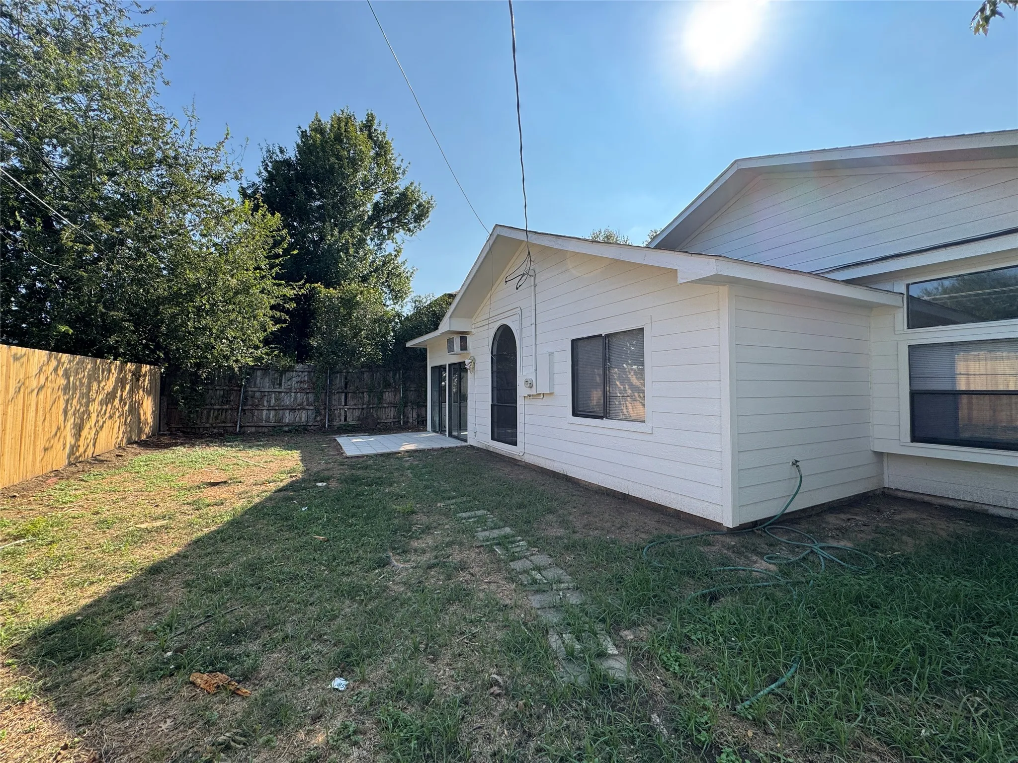 Exterior featuring white horizontal siding, a private backyard with a wood fence, and a concrete patio