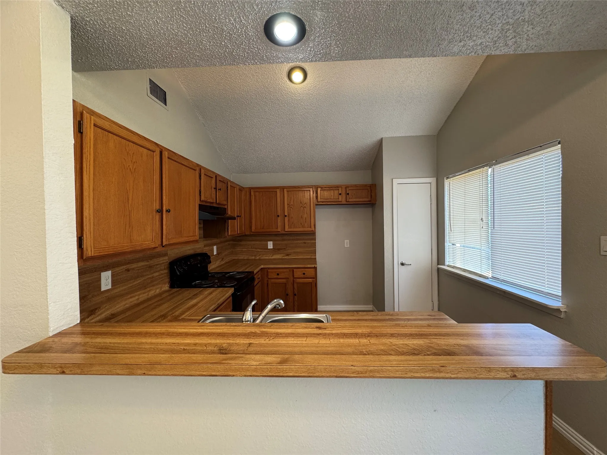Kitchen featuring wood-finish countertops, wood cabinetry, a stainless steel sink, and recessed lighting