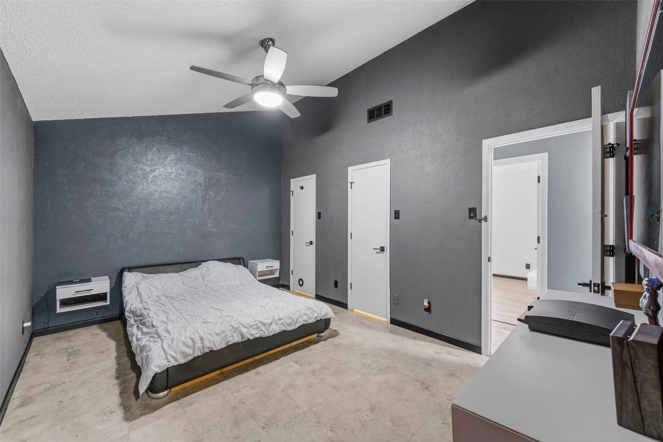 Vaulted ceiling with a contemporary ceiling fan, modern wall sconces, wood-finish flooring, and white interior doors