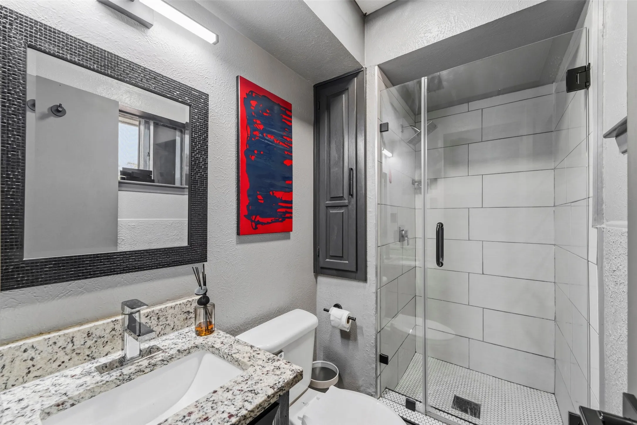 Frameless glass shower enclosure with subway tile surround and mosaic floor