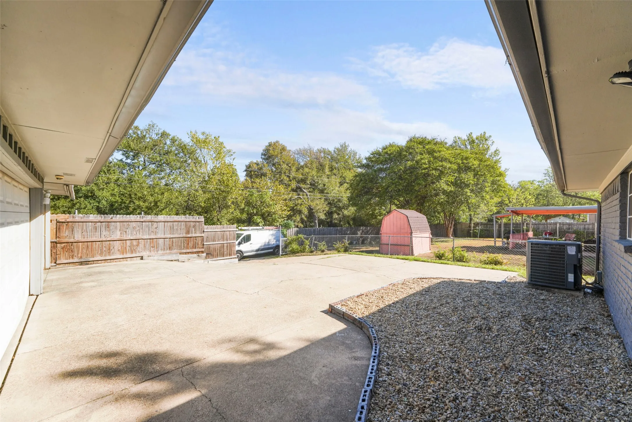 Expansive concrete patio with gravel border and wood privacy fencing