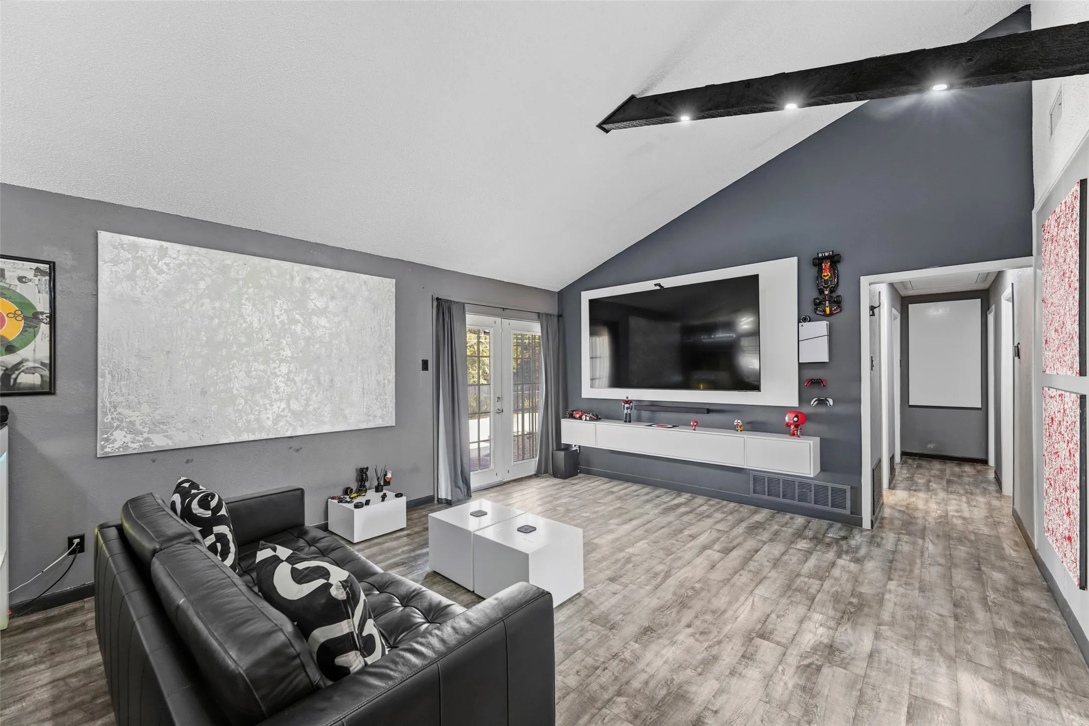 Vaulted ceiling with exposed beam, recessed lighting, wood-finish flooring, and double French doors with transom windows