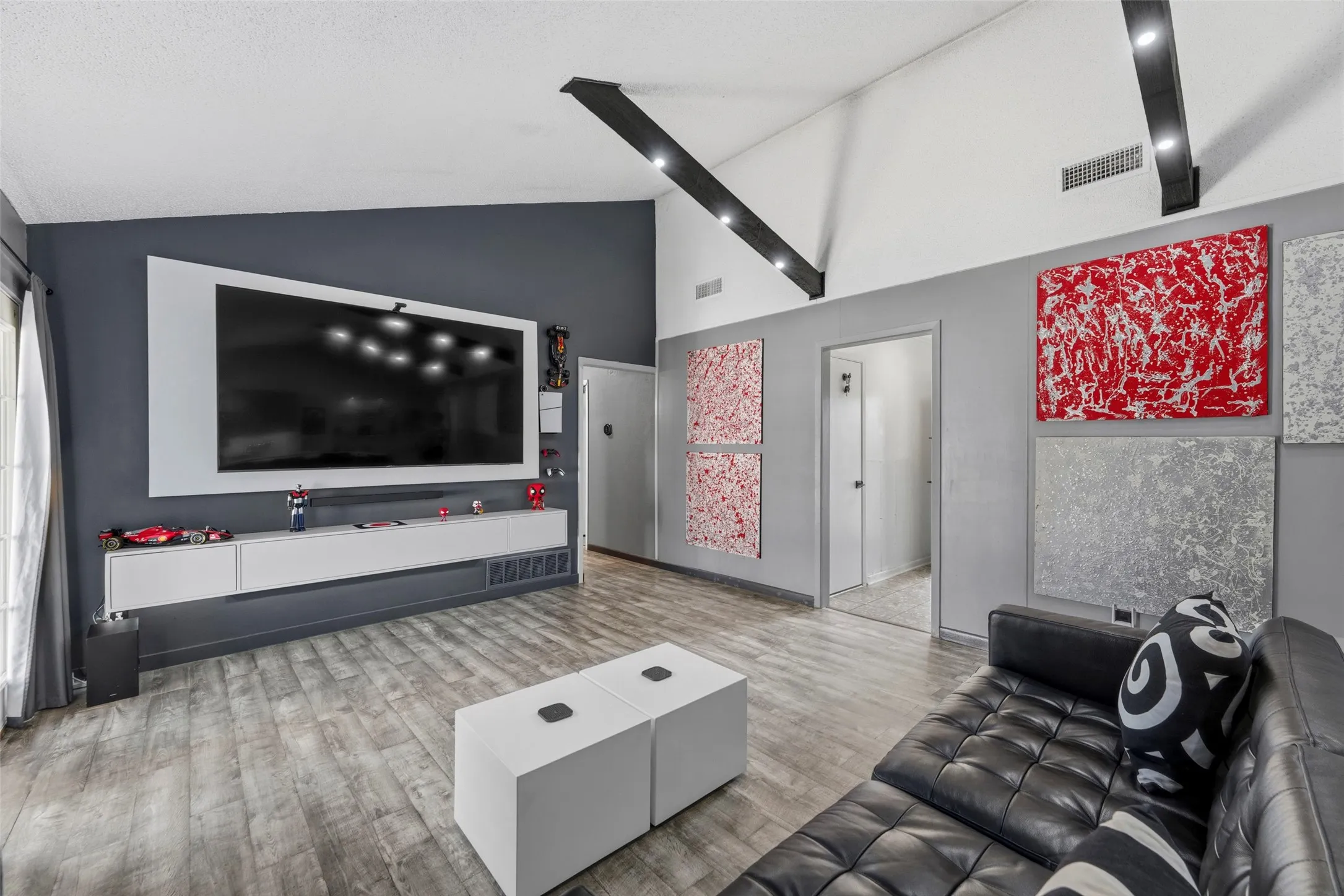 Vaulted ceiling with exposed beams, wood-finish flooring, built-in media console, and recessed lighting