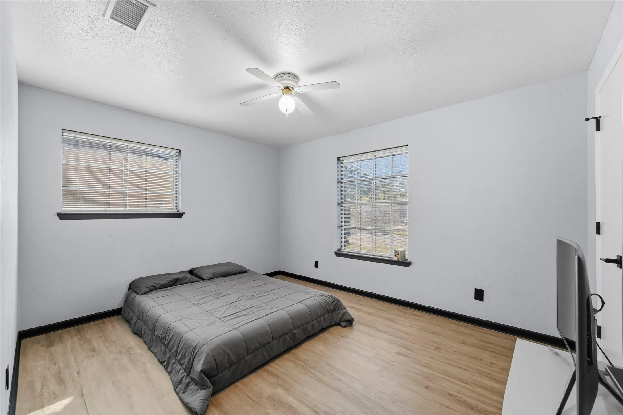 Wood-finish flooring, white walls, and two windows with black trim