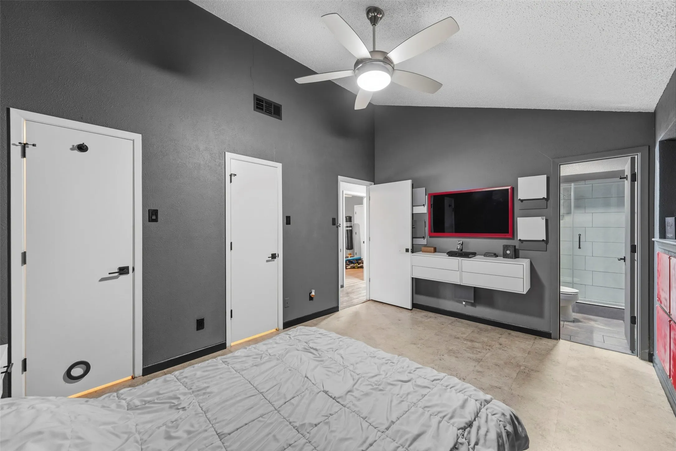 Vaulted ceiling, ceiling fan, hard-surface flooring, built-in media console, and glass-enclosed shower