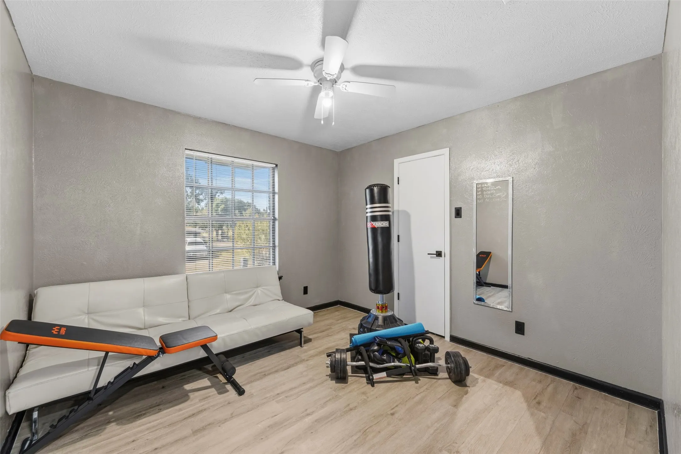 Recessed window with grid panes, overhead ceiling fan with light, and wood-finish flooring