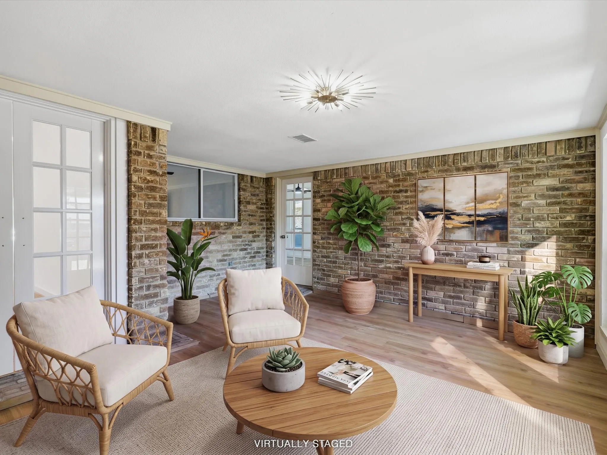 Brick accent wall, wood-finish flooring, white crown molding, recessed lighting, and white French doors