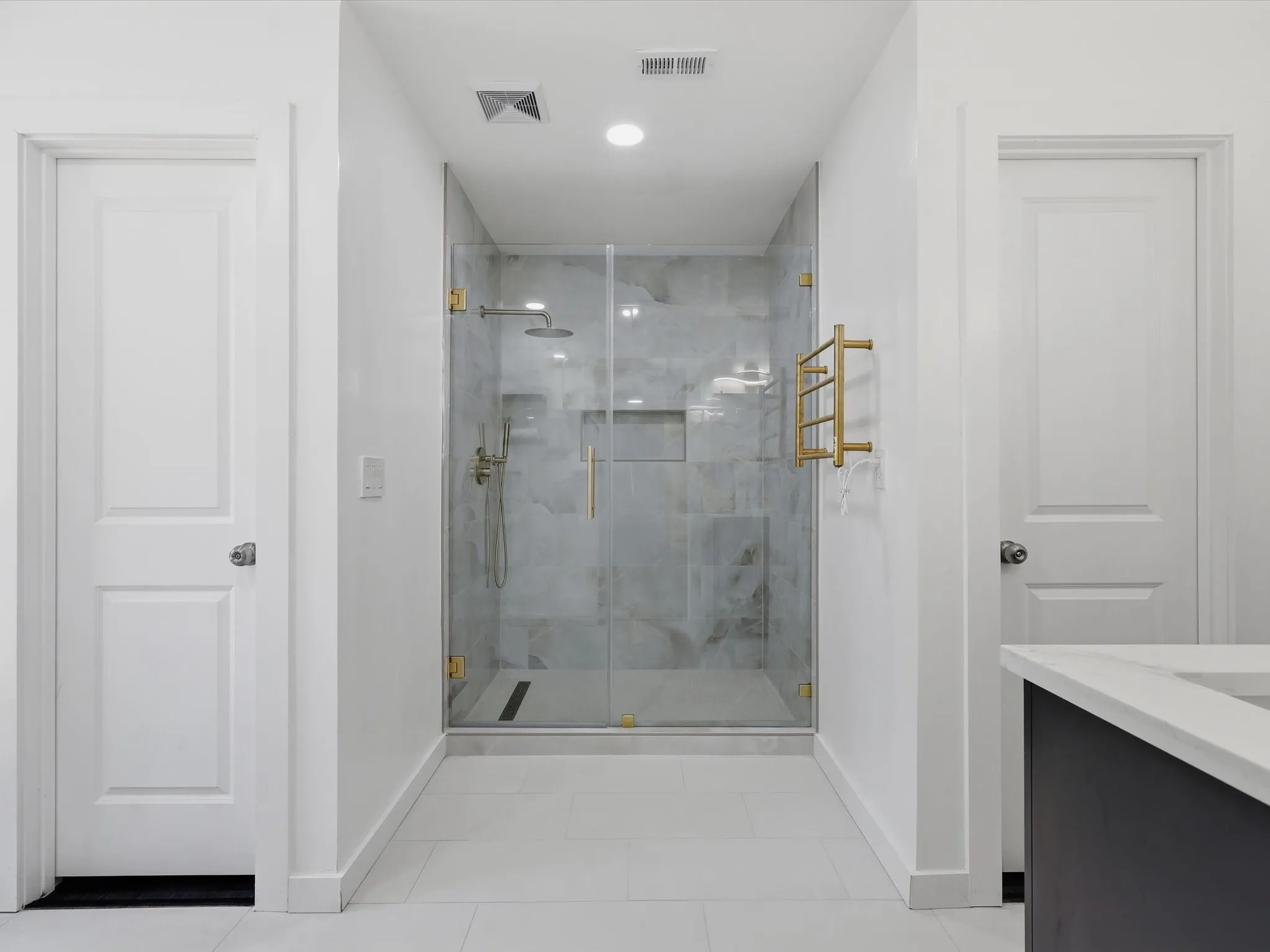 Glass-enclosed shower with gold-finish hardware, recessed lighting, and a rainfall showerhead