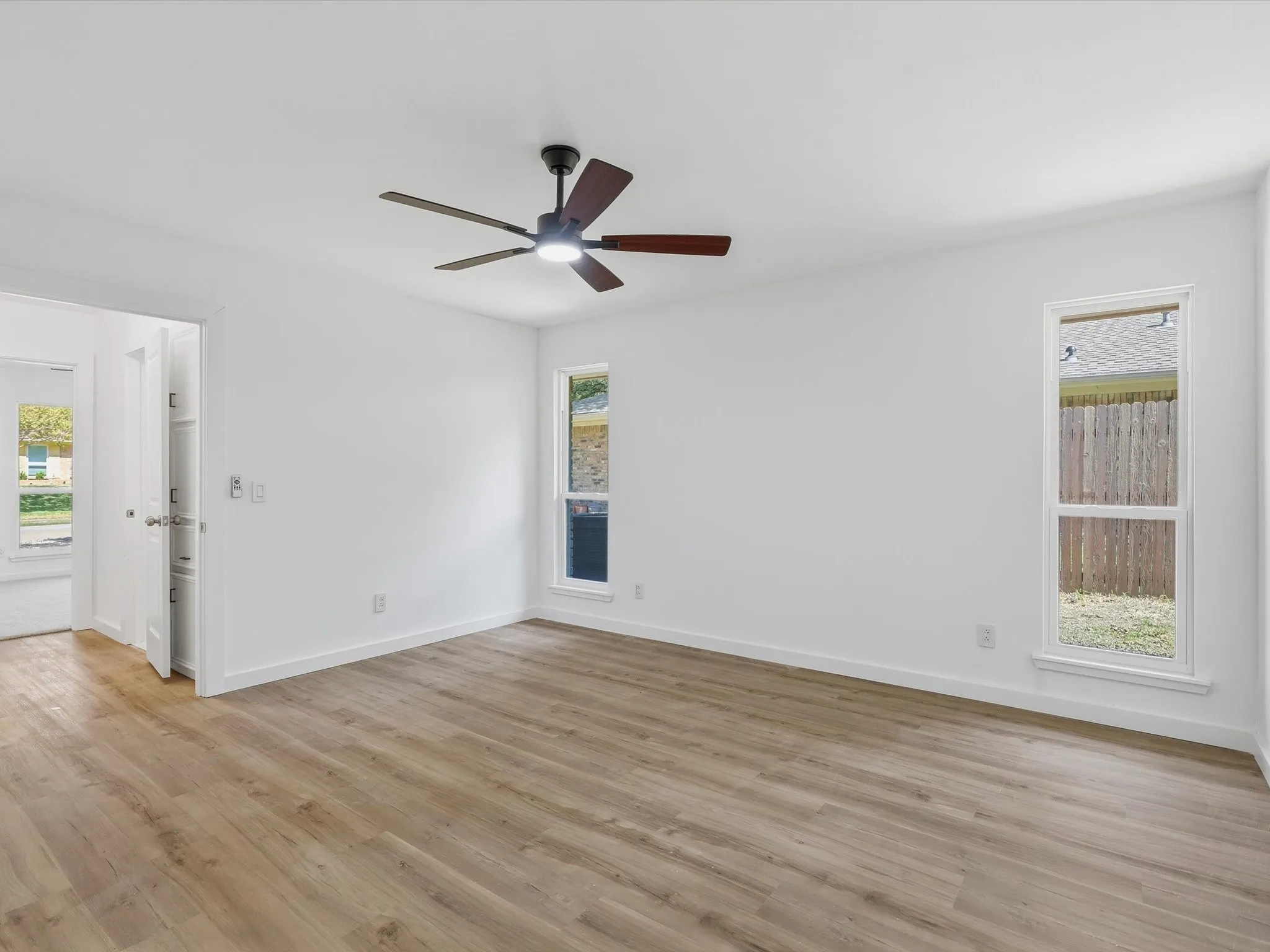Hardwood-finish flooring, white walls, and a ceiling fan with integrated lighting