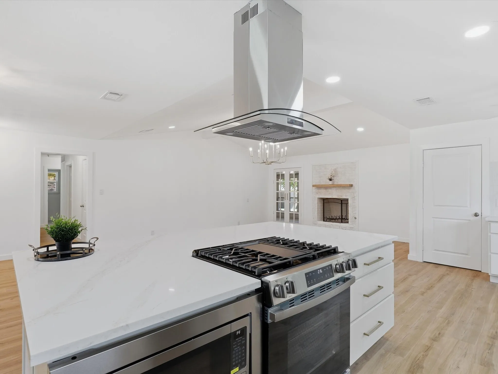 Kitchen island with a built-in stainless steel range, white countertop, and stainless steel microwave